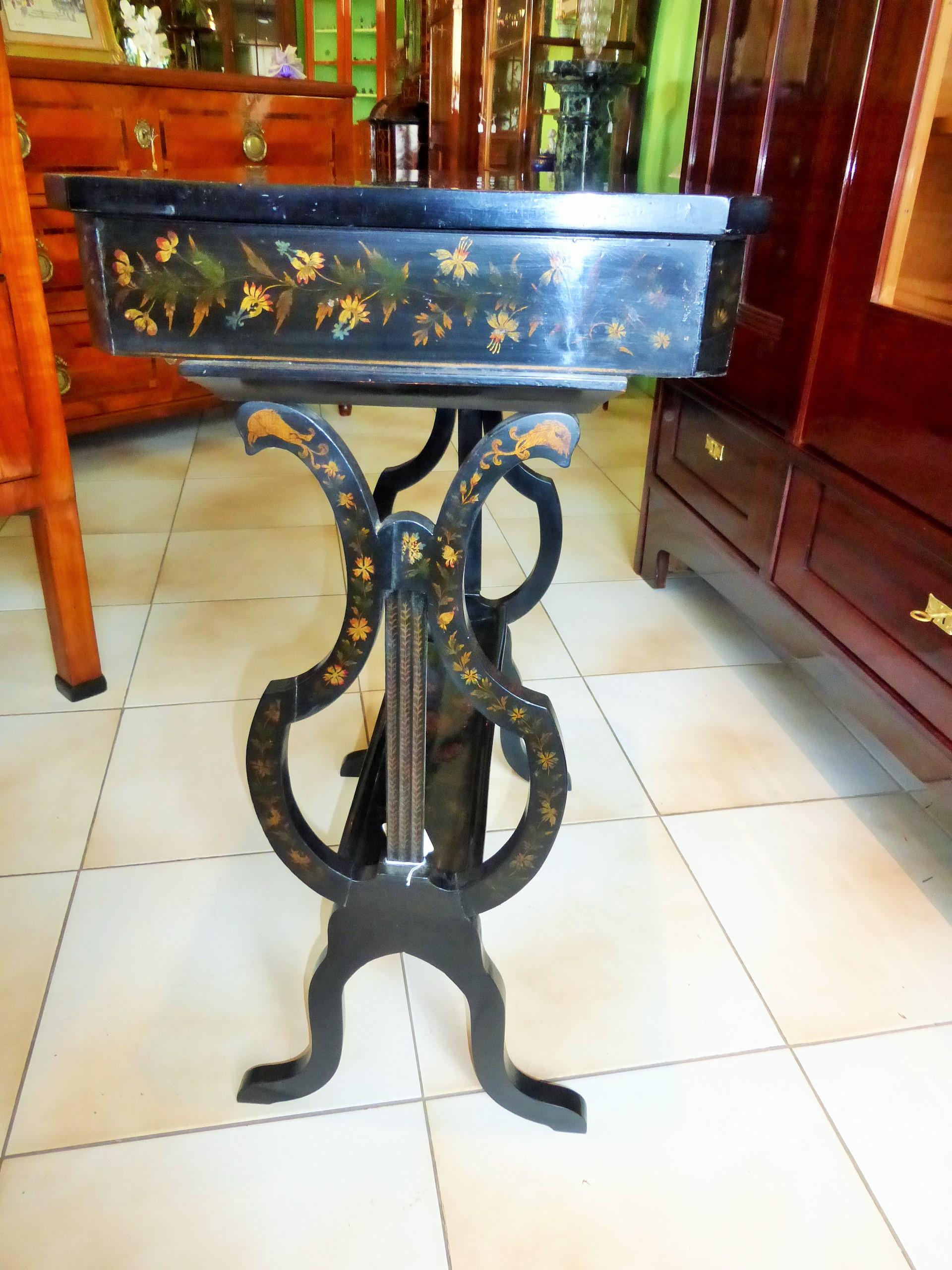 Antique and unique Biedermeier sewing table from circa 1830. Particularly beautiful is the lyra shape of the legs, which are connected to a semi-circular bridge. Presumably, the beautiful paintings, reminiscent of a flower meadow, were later added