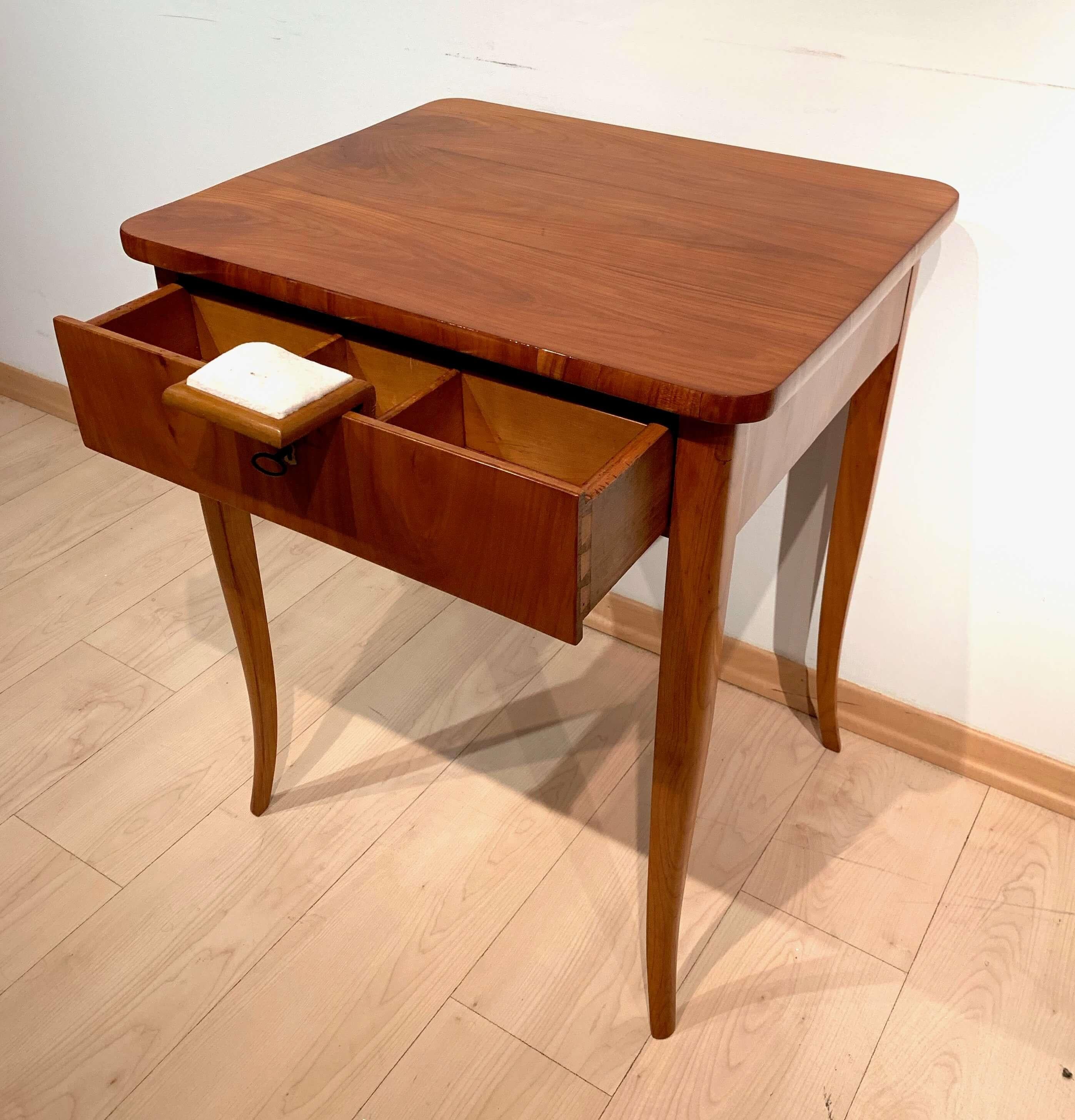 Classic cherry wood Biedermeier sewing table from Austria about 1925/30.

Cherry veneered (plate and apron) and solid wood (legs). 
Raised on curved square tapered legs.
One drawer with interior including fold-out sewing cushion. 
Bone (?) inlay