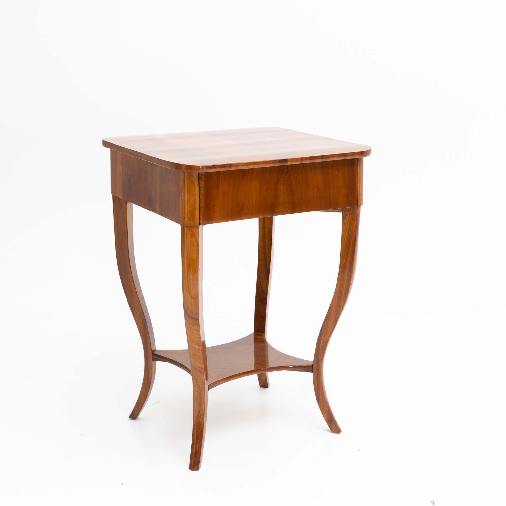 Small Biedermeier sewing table in cherry veneer with s-shaped legs, intermediate brace and rounded corners and a drawer with compartment division. Restored and hand polished condition.