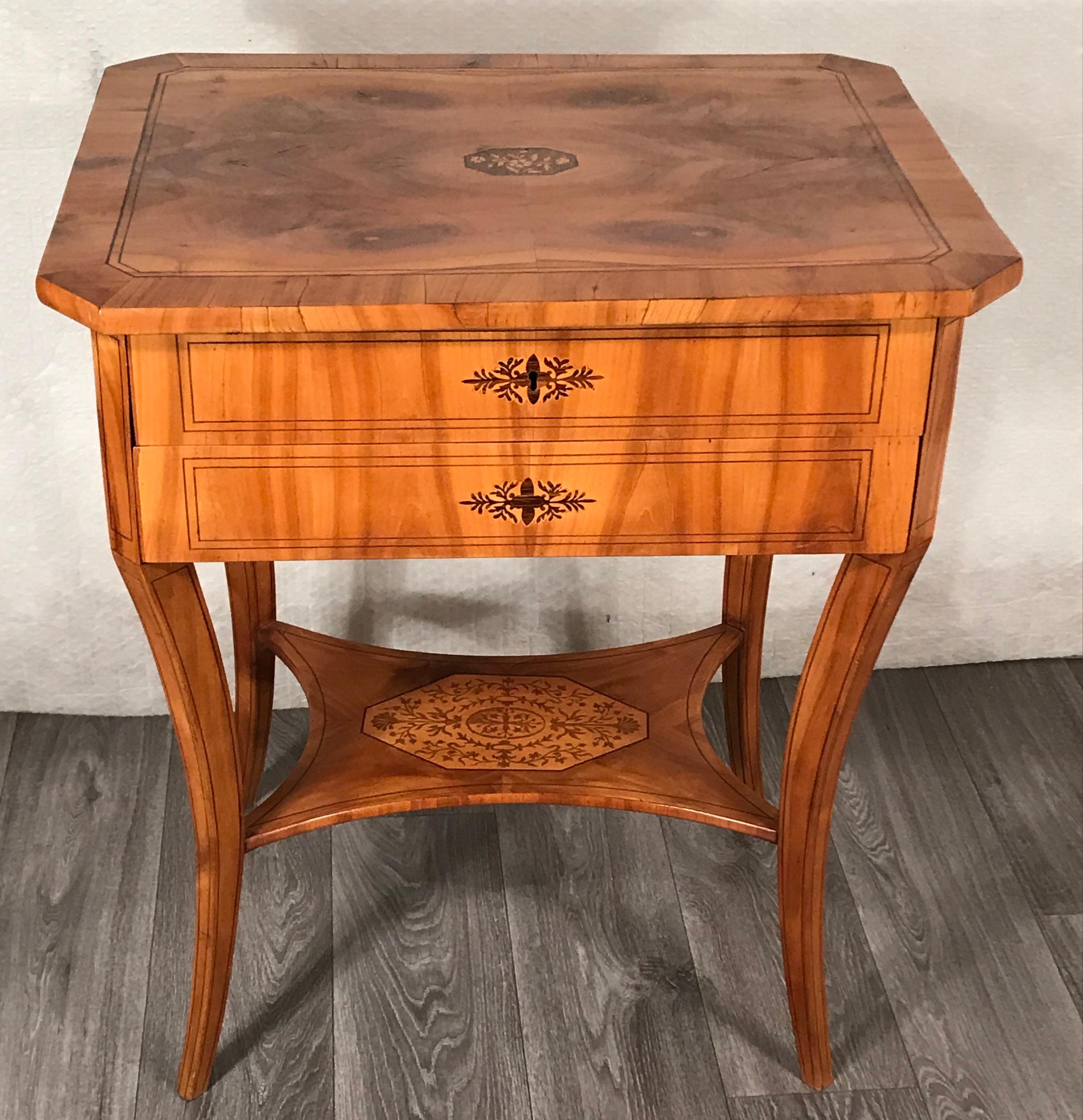 Biedermeier sewing table, South German 1820-25. 
Cherry veneer with beautiful floral marquetry details in maple and plum wood. The sewing table has two drawers, the inside of one of them has several compartments and a flippable pin cushion. The