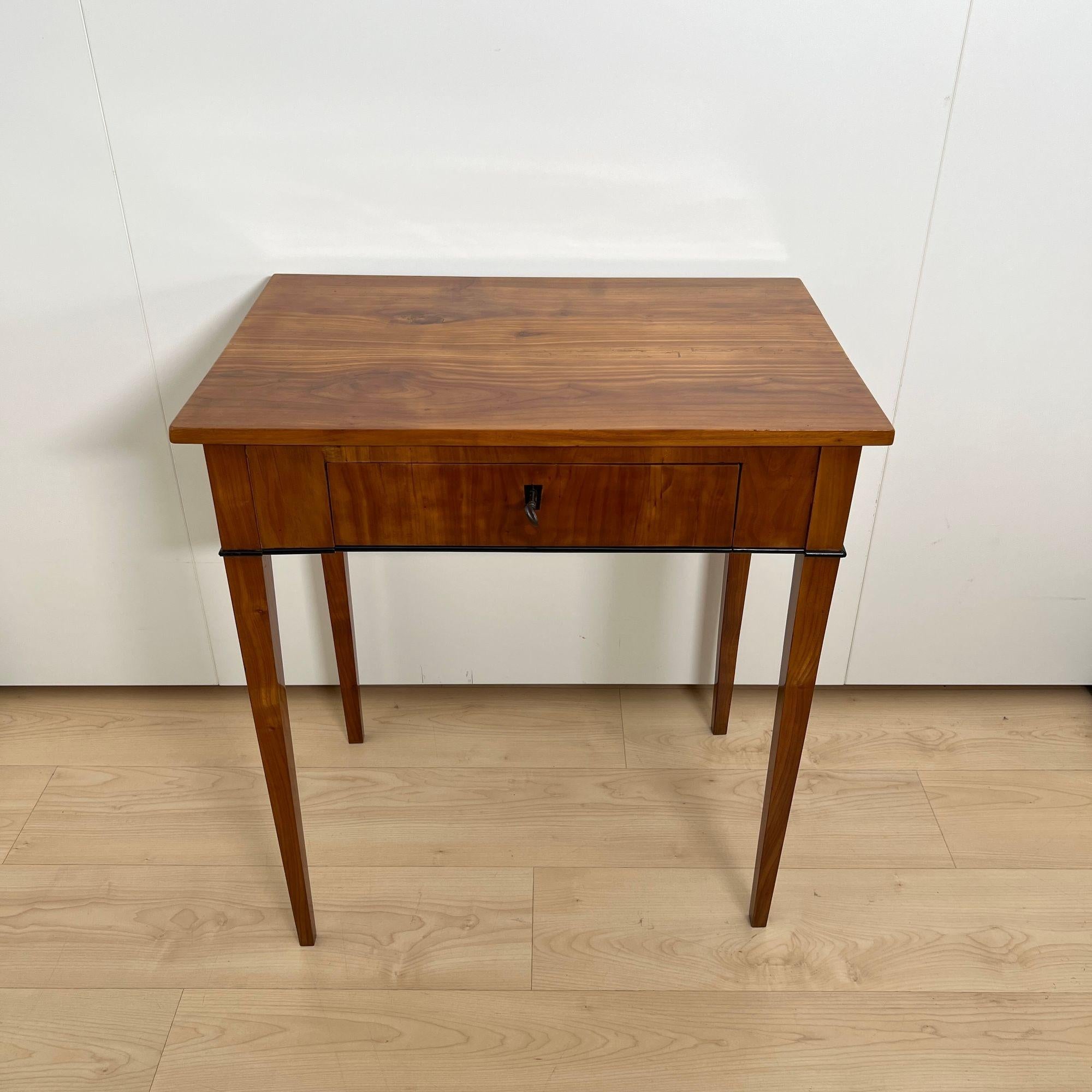 Beautiful, straightlined Biedermeier side table with drawer from South Germany around 1820.
Solid cherry wood (top) and veneered (apron) on softwood. Solid cherrywood tapered square legs.
Ebonized strips and key escutcheon. Front drawer with