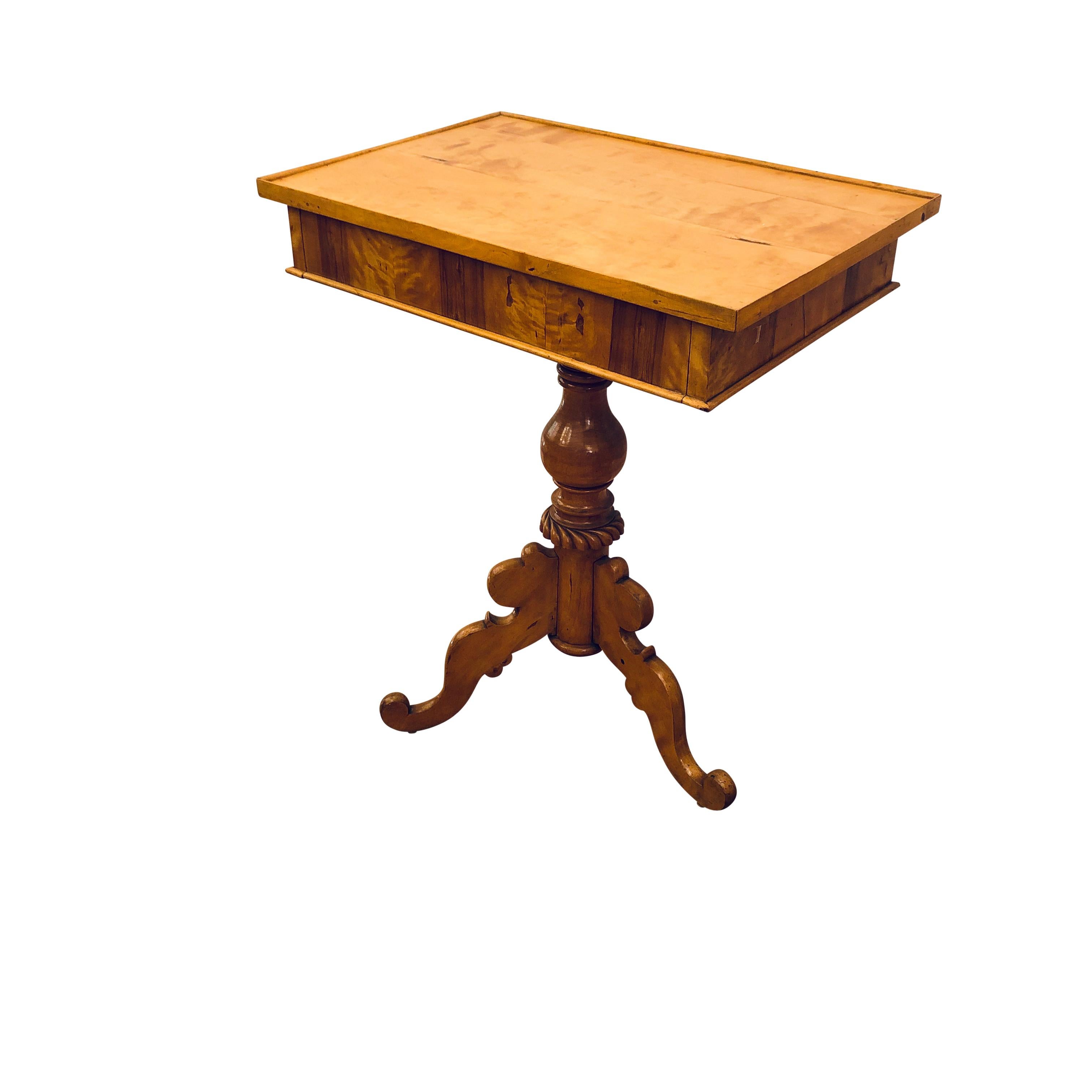 Ein dreibeiniger Sockel ist sehr stabil und trägt eine großzügige Tischfläche, deren Flächen mit erstklassigen, farblich abgestimmten Birkenfurnieren verziert sind.
  