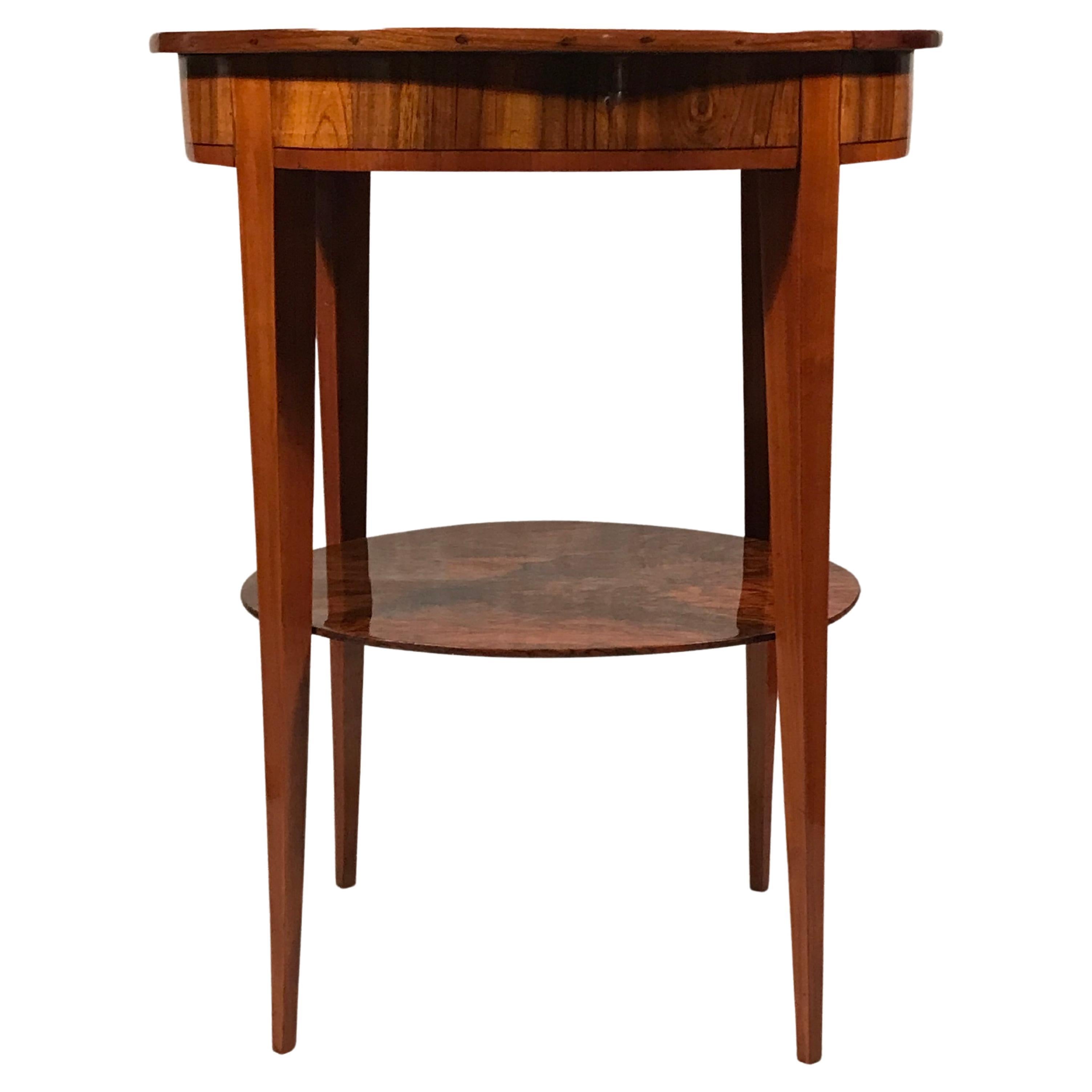 This exquisite Biedermeier side table dates back to 1815-20 and comes from southern Germany. The oval table has a gorgeous walnut veneer. The oval top with apron has additionally a darker wood ribbon inlay. The lower part of the table has an