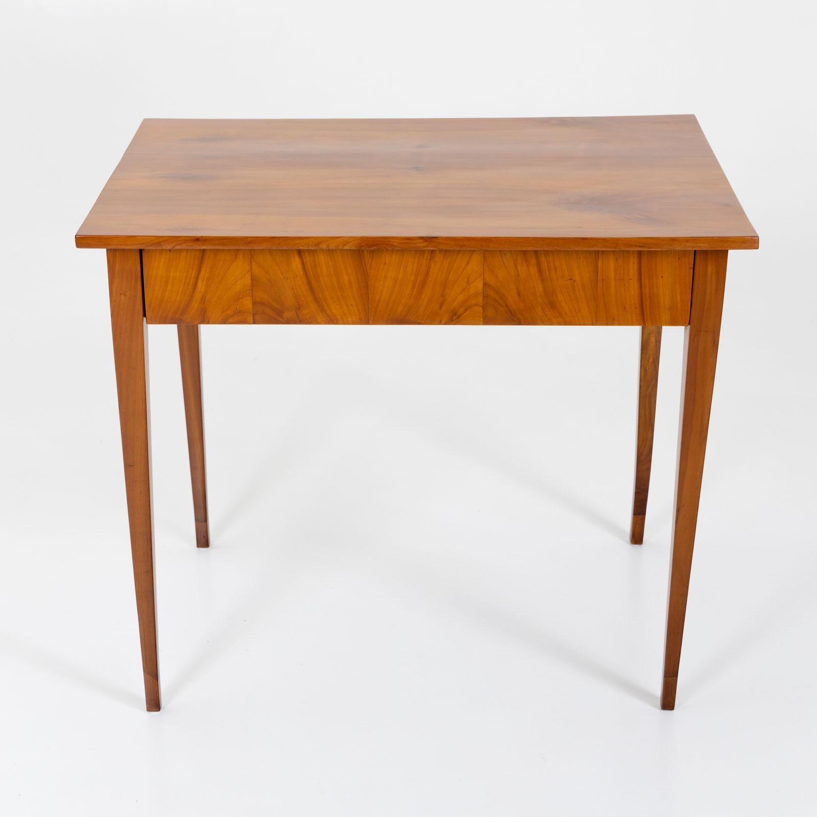 Biedermeier side table in cherry with one drawer and rectangular table top. The table stands on high square tapered legs and has been expertly restored and polished by hand. 