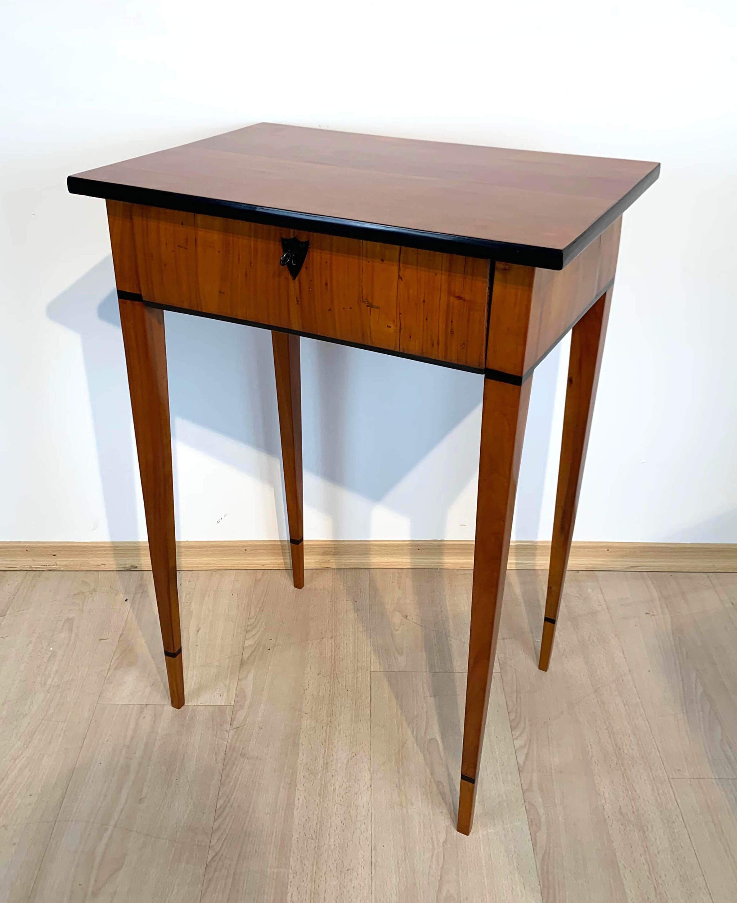 Strict, elegant Biedermeier side table with drawer, cherry, South Germany, circa 1820

Cherry veneer and solid. One lockable drawer with interior and ebonized key plate. Ebonized edge and surrounding rings. 
Restored condition, refinished with
