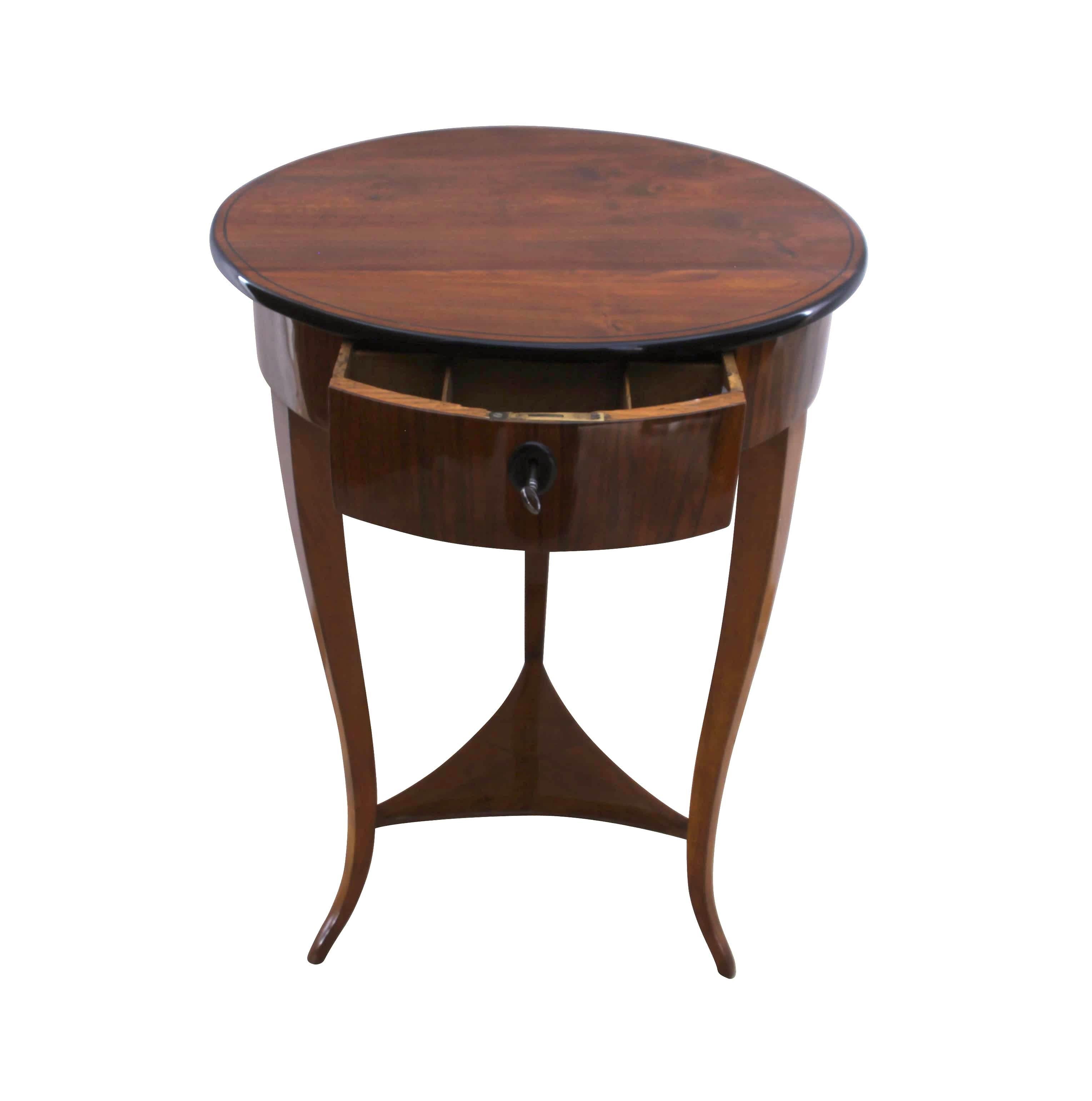Round, elegant Biedermeier side table with drawer and middle plate.
Walnut veneered and solid wood.
Curved legs and ebonized edge and ink line.