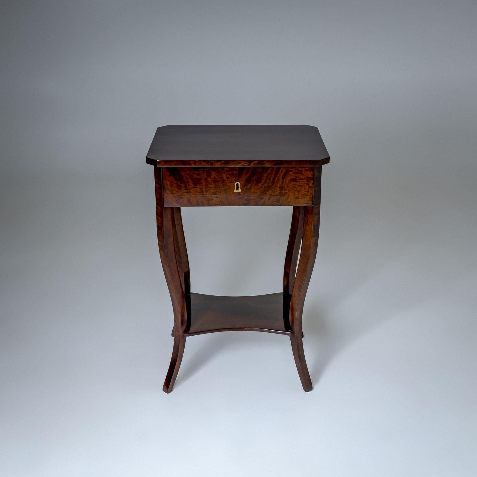 Small Biedermeier side table with one drawer and a quatrefoil intermediate board and curved legs. The table top is bevelled at the corners. The drawer is equipped with a partition inside. The table has been restored and polished.