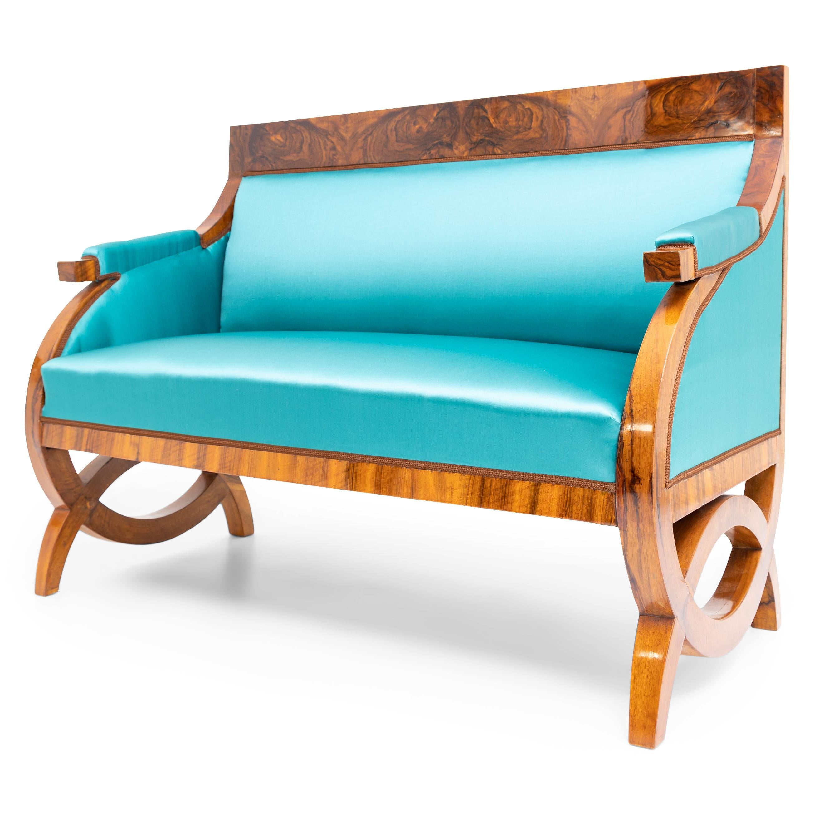 Biedermeier sofa on segment-shaped legs with rounded side parts, short armrests and backrest with straight burl wood veneered top. The sofa is newly covered with a light blue satin fabric. Solid and veneered walnut. Hand polished, restored condition.