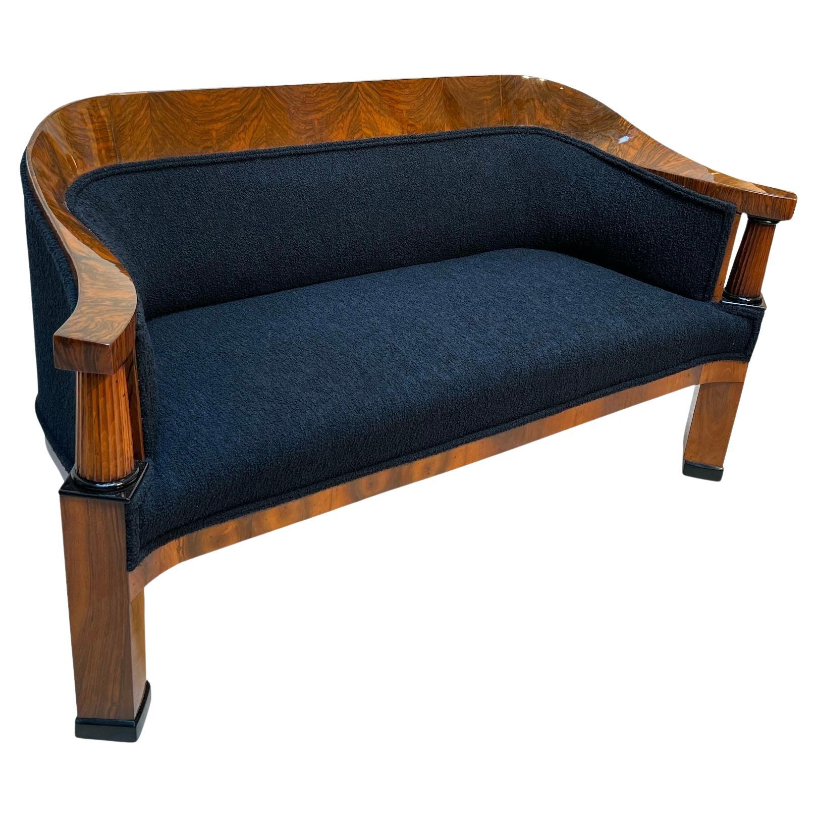Precioso sofá neoclásico Biedermeier de Viena, Austria, hacia 1825.
Nogal chapado y nogal macizo. Dos columnas enteras estriadas de haya con capiteles y bases ebonizados.Recién revestidas con tela negra de teddy (Bouclé) y doble keder. El respaldo