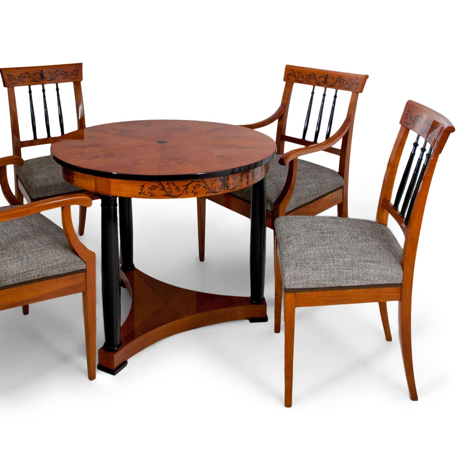 Sitting group, consisting of one table, two armchairs and two chairs out of cherry wood. The round table stands on a trefoil base and ebonized columns support the top. The edge is ebonized as well and the rail shows floral designs that are repeated