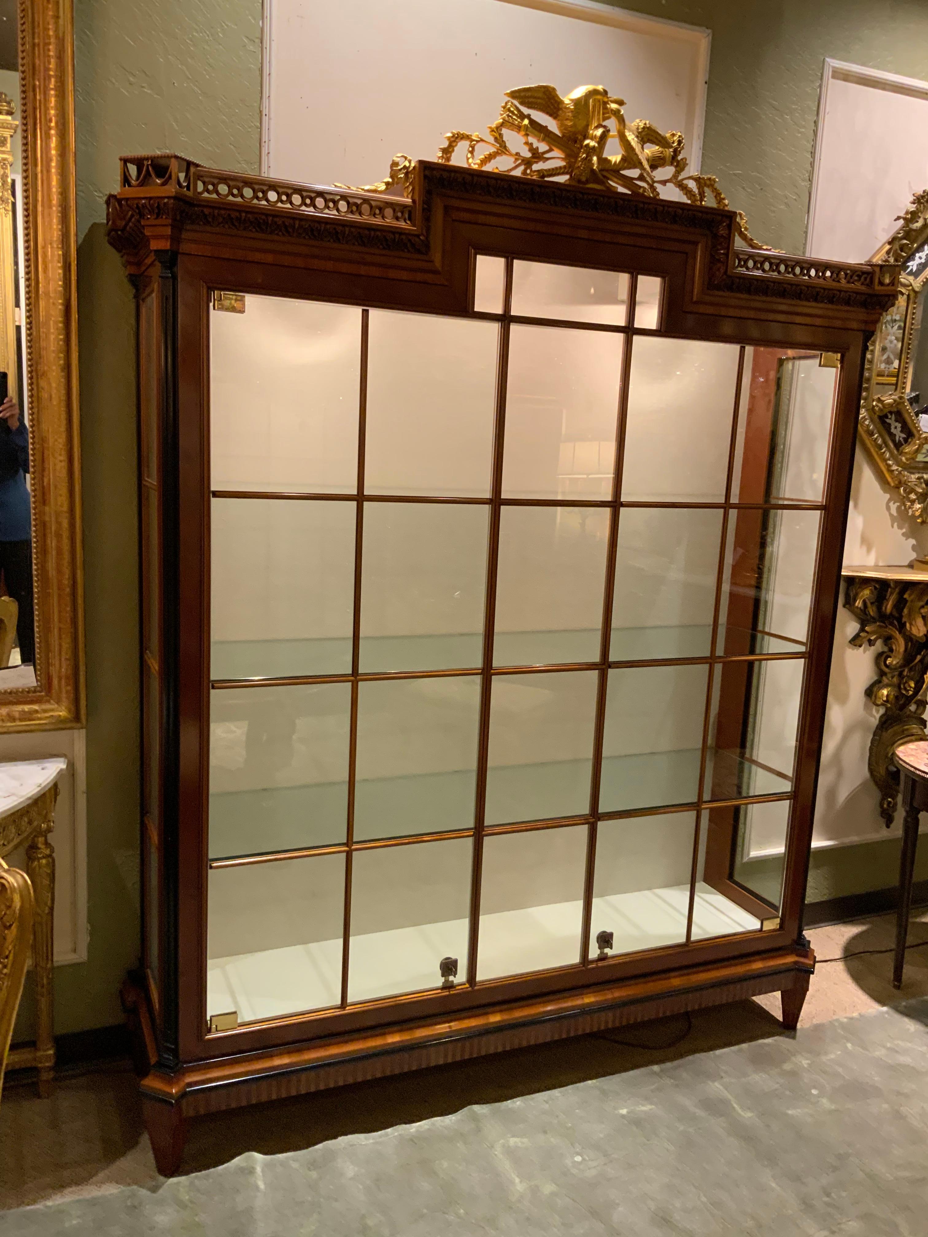 Exceptional quality cabinet that has beautiful detail and a hand carved gold leaf crown.
Made of yew wood and cherrywood with ebony trim. The crown depicts doves with
A torch and quiver. The cabinet has three glass shelves.