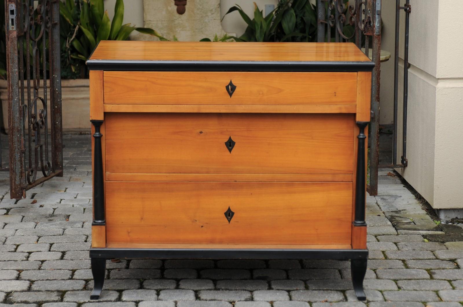A German Biedermeier style walnut three-drawer commode from the late 19th century, with ebonized accents and hidden drawers. Born in the later years of the 19th century, this exquisite Biedermeier style commode features a rectangular planked top
