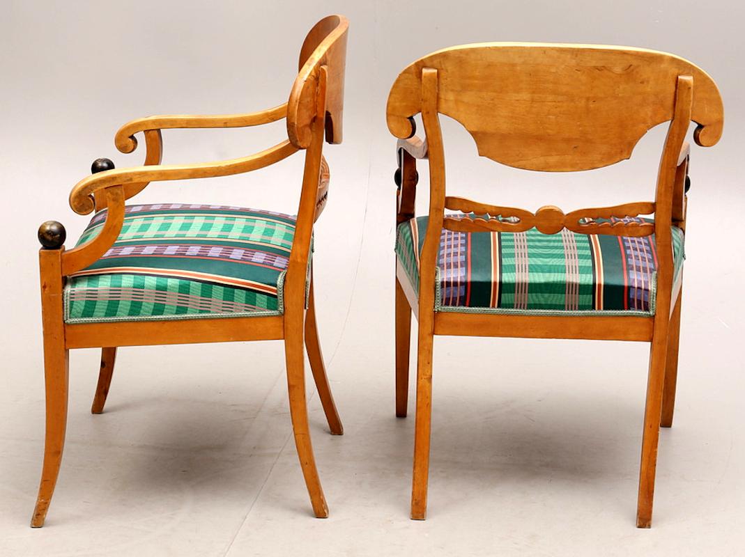 Swedish Biedermeier Empire pair of carver chairs in highly quilted golden birch veneers finished in the Classic honey color French polish finish with ormolu roundel on the arms.

They have fully webbed seats for maximum comfort and the gently