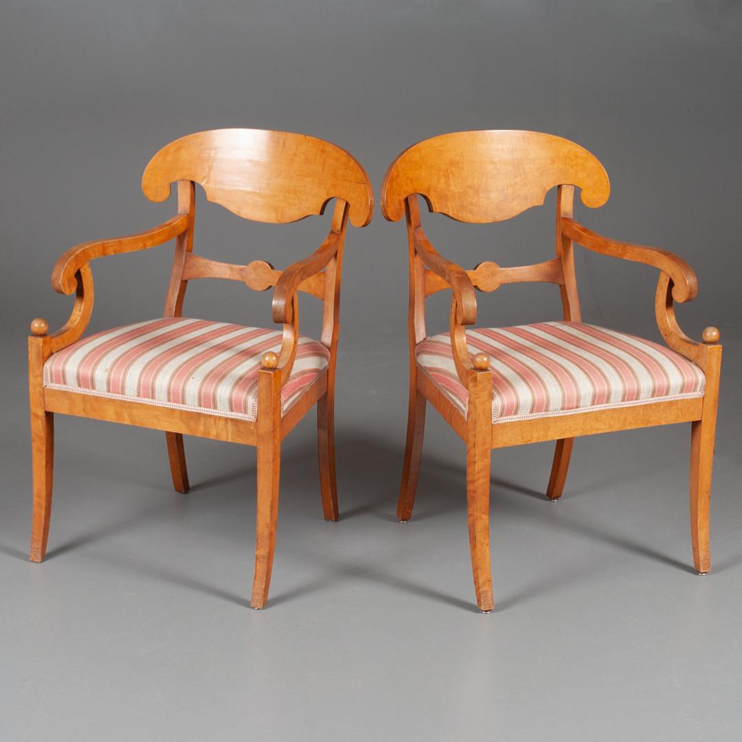 Swedish Biedermeier Empire pair of carver chairs in highly quilted golden birch veneers finished in the Classic honey color French polish finish with ormolu roundel on the arms and fan motifs in the seat back.

They have fully webbed seats for