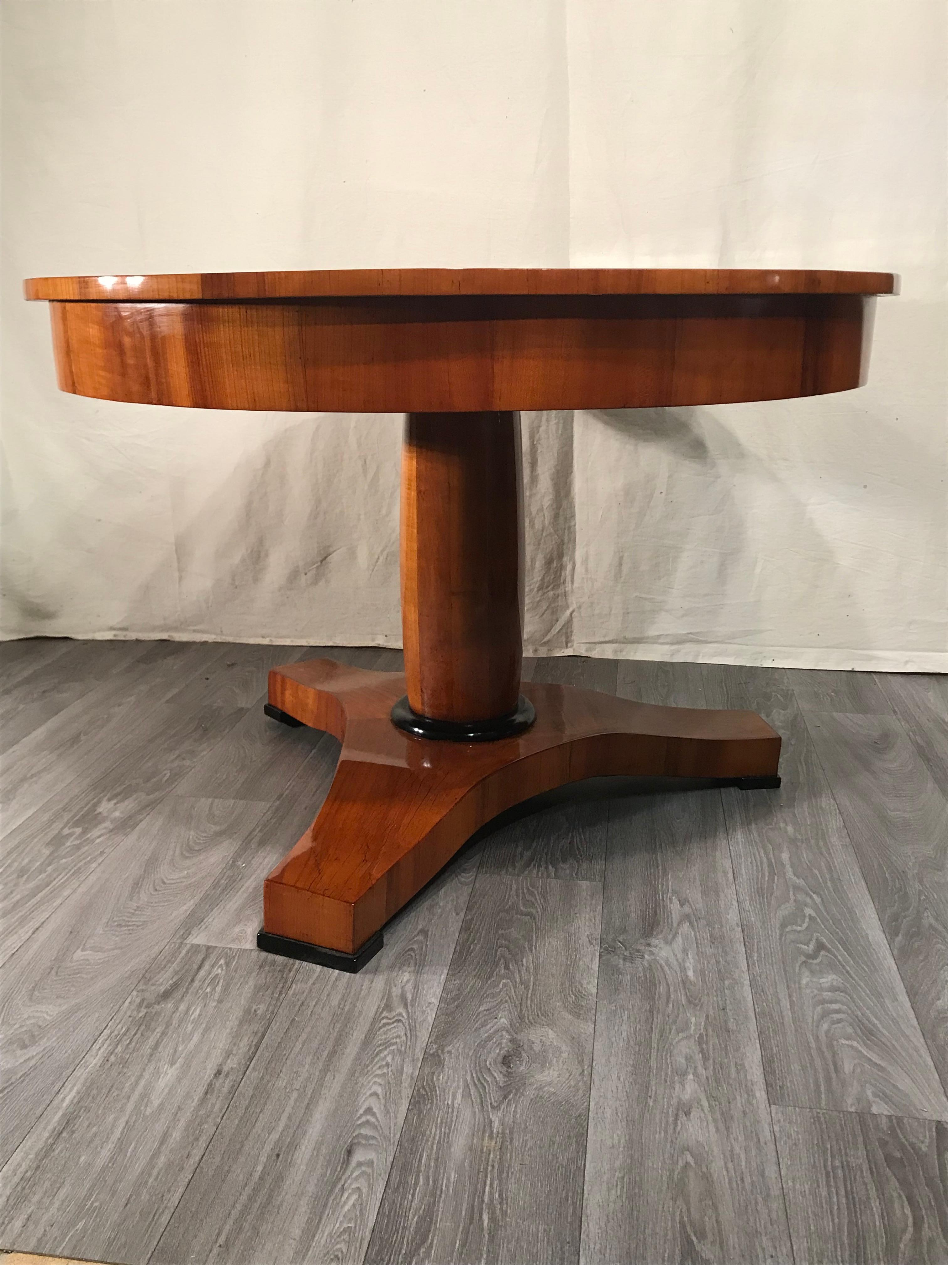 Dieser originale Biedermeier-Tisch stammt aus der Zeit um 1820-30 und kommt aus Süddeutschland. Der Tisch hat eine zentrale Säule, die auf einem dreifüßigen Sockel steht. Alle Teile sind mit einem sehr schönen Kirschbaumfurnier versehen. Die Platte