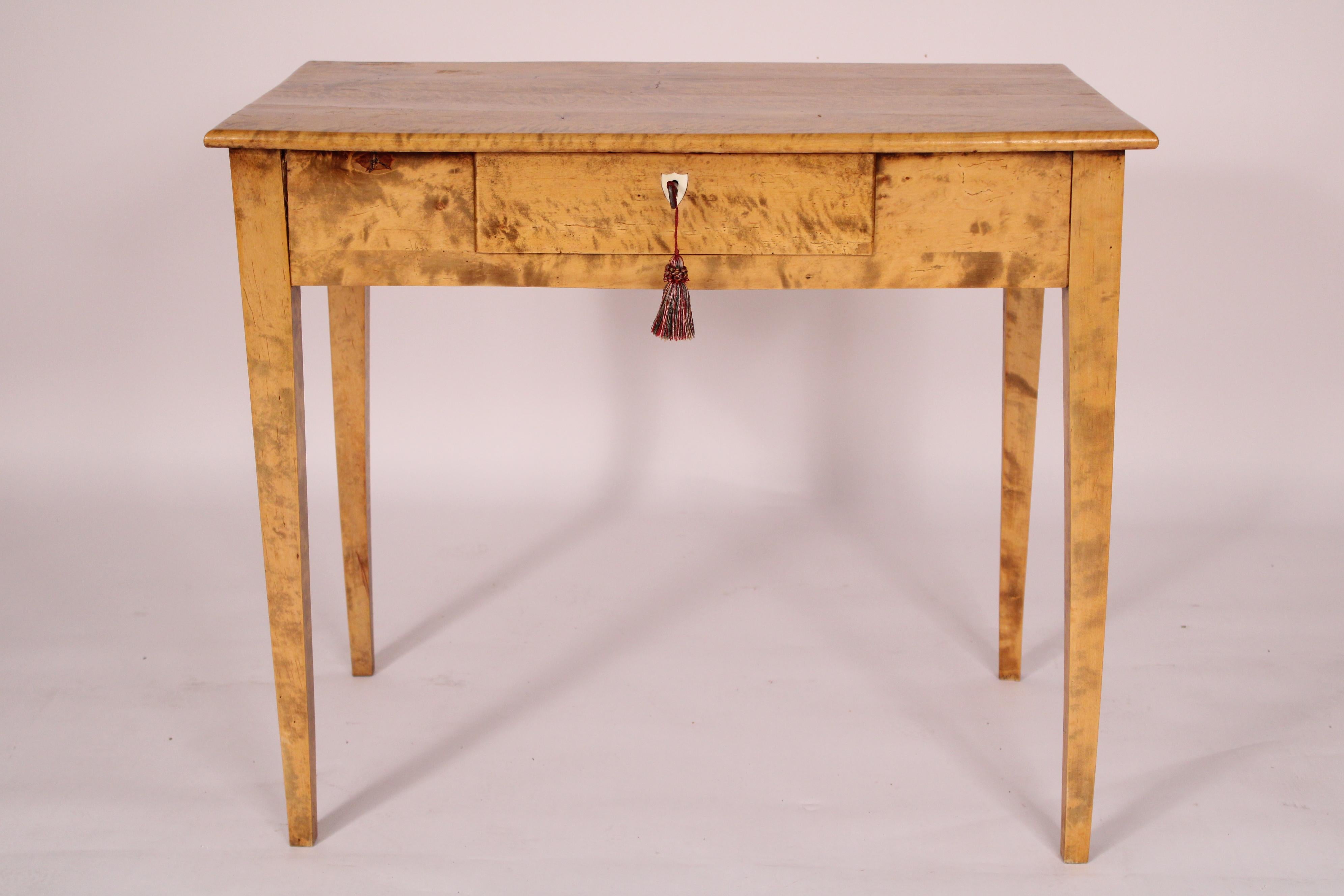 Biedermeier tiger maple writing table, 19th century. With a 4 board top with rounded front and side edges, a frieze drawer with a bone shield shaped escutcheon, resting on square tapered legs. This writing table would be at home in either a