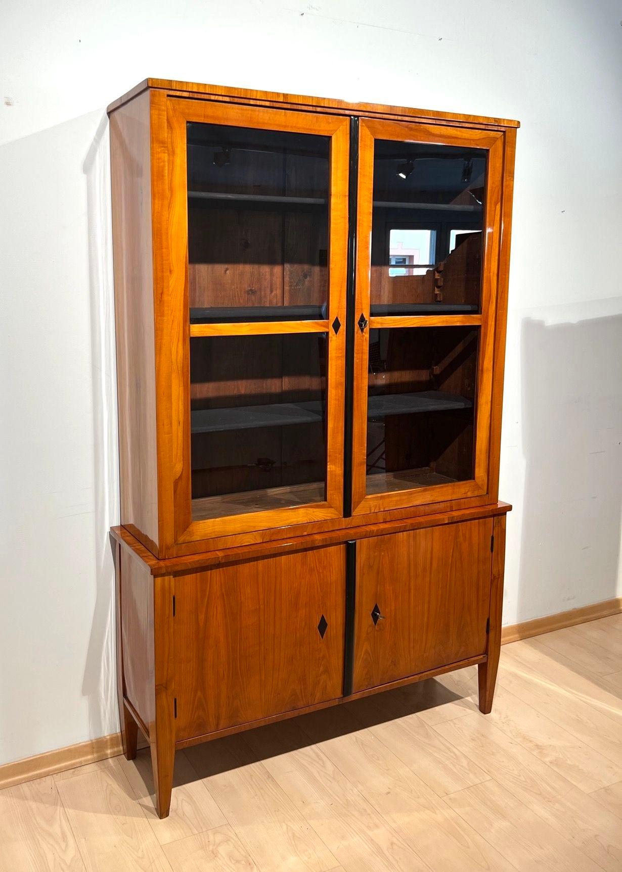 Beautiful unadorned Biedermeier Vitrine or Top Showcase, display case or two-part bookcase in cherry veneer from south Germany around 1830.
Cherry wood veneered on softwood. Upper part as a two-door showcase with glass. Ebonized gutter and diamond