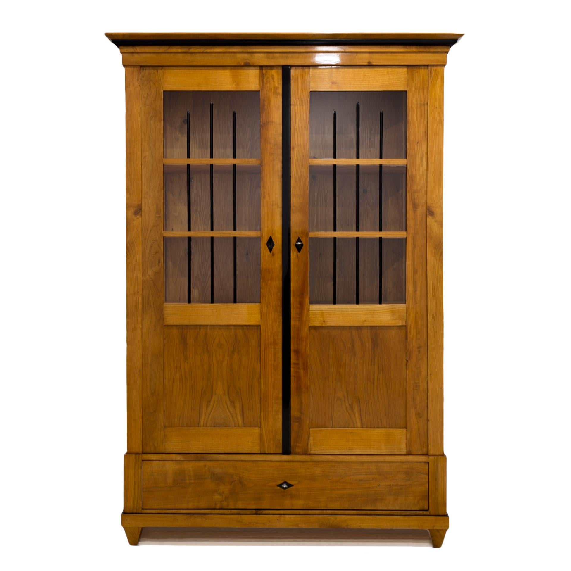 This Biedermeier style vitrine comes from Germany from 19th century. It is made of solid cherrywood. The piece is after complete and professional renovation process. The surface is refinished with shellac polish, applied by hand, which apart from a