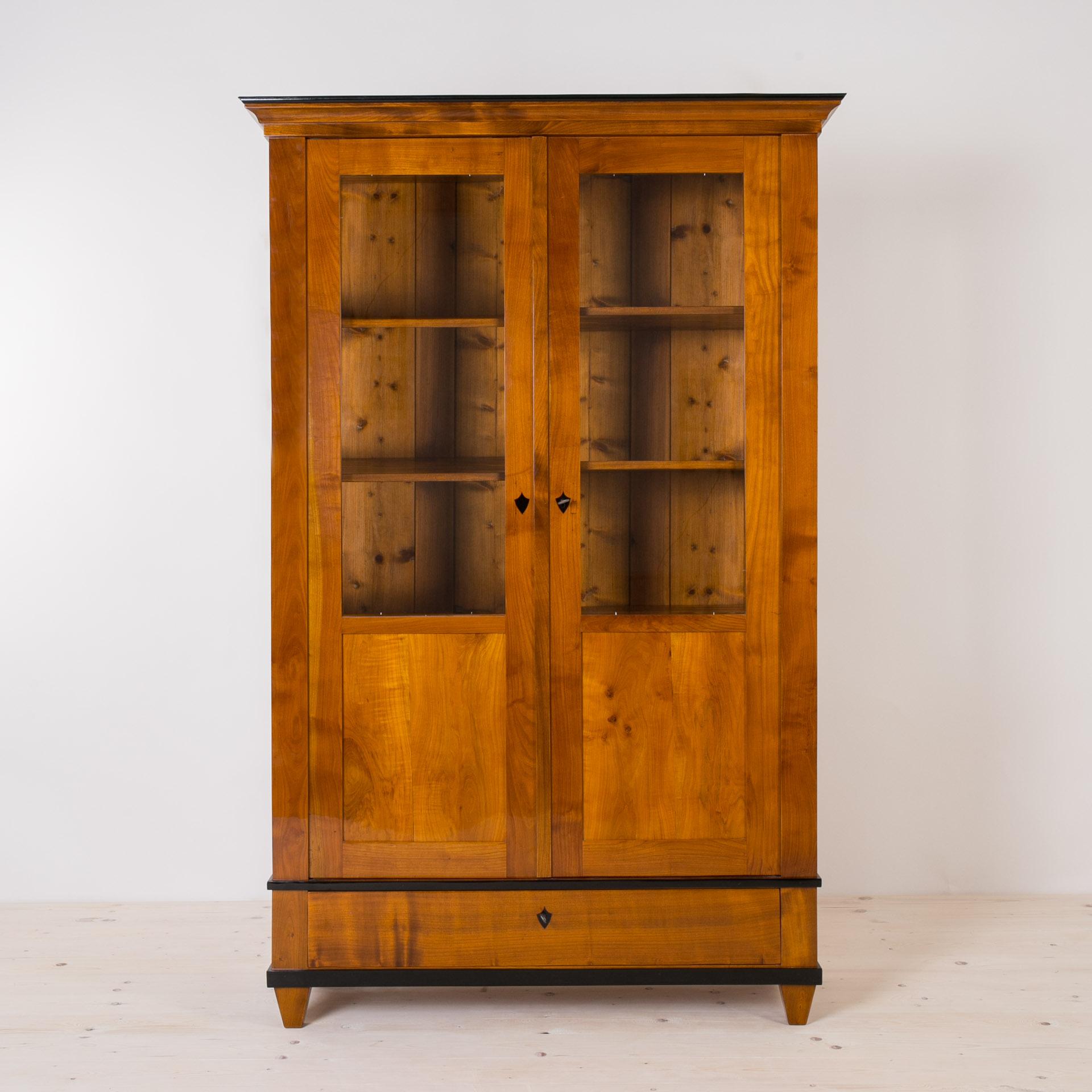 This beautiful cherrywood vitrine comes from Germany and was made in 19th century (the Biedermeier period). The construction is made of solid cherrywood. The piece features 3 practical shelves and one spacious drawer below the main section. It is