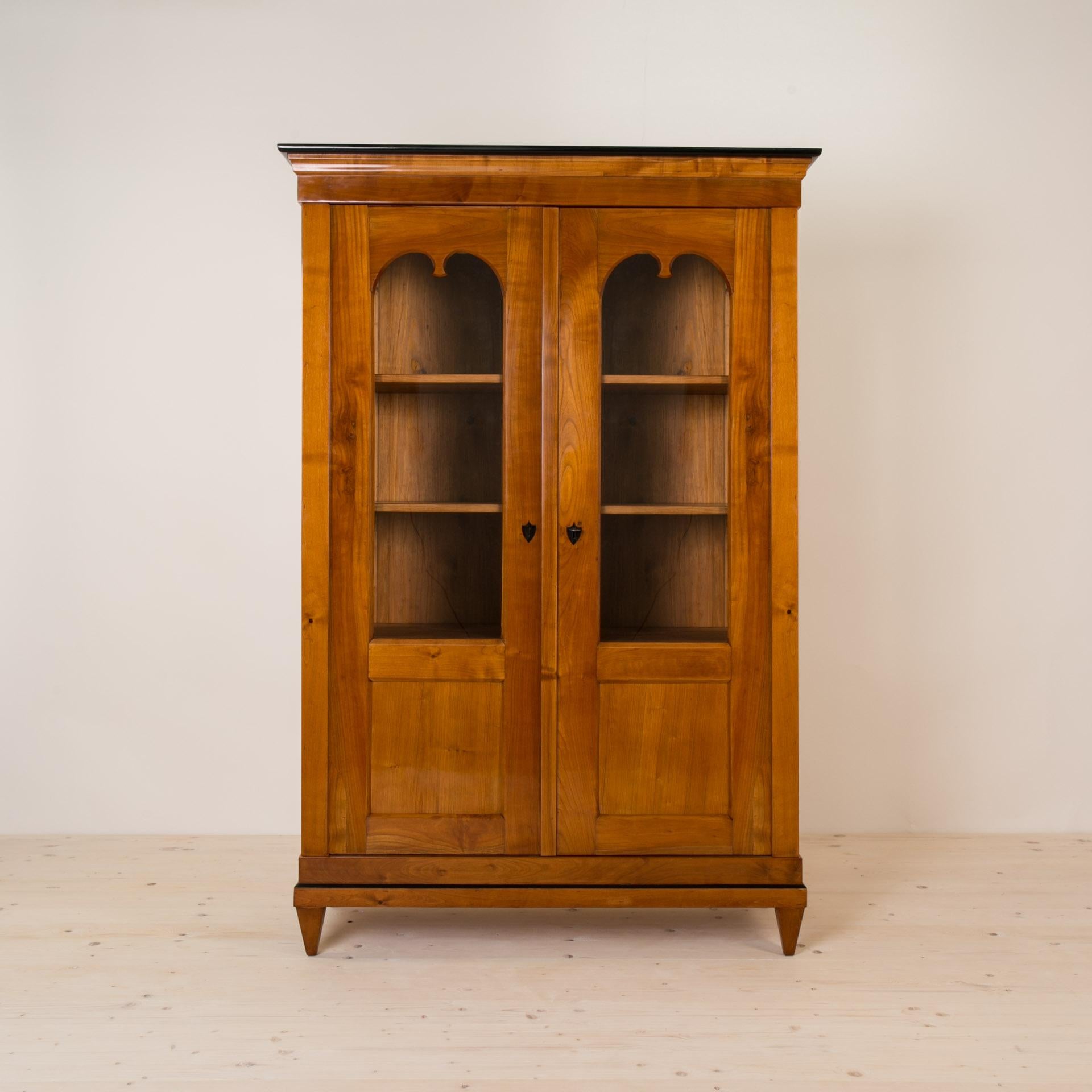 Diese schöne Kirschholzvitrine stammt aus Deutschland und wurde im 19. Jahrhundert (Biedermeier) hergestellt. Die Konstruktion ist aus massivem Kirschholz gefertigt. Das Möbelstück verfügt über 3 praktische Einlegeböden. Er steht auf vier spitz