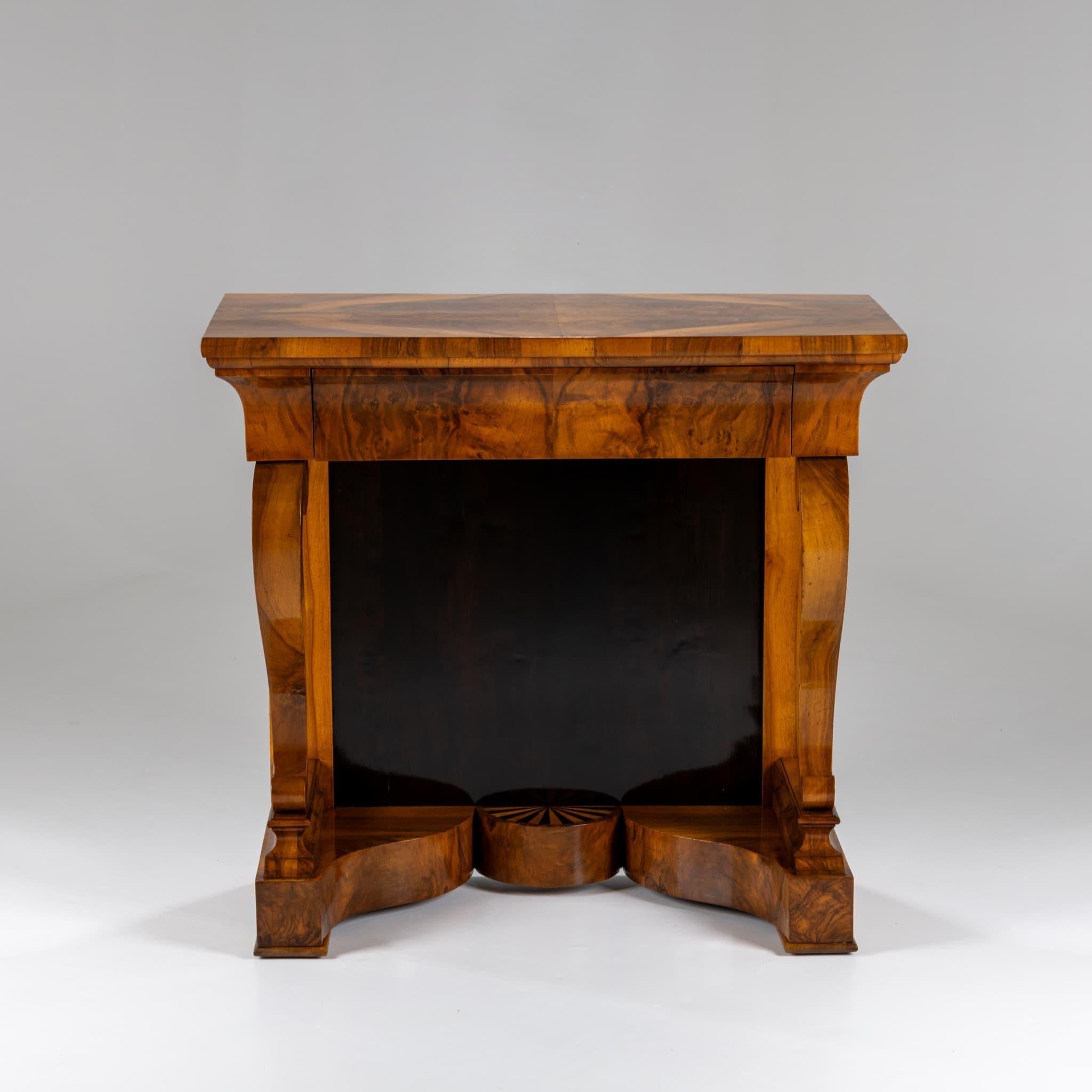 Biedermeier-Wandkonsole in Nussbaum mit einer Schublade und doppelreihigen Beinen auf beiden Seiten. Der elegant gearbeitete Sockel weist ein halbkreisförmiges Design mit radialen Intarsien auf, die abwechselnd aus hellem und dunklem Holz bestehen.