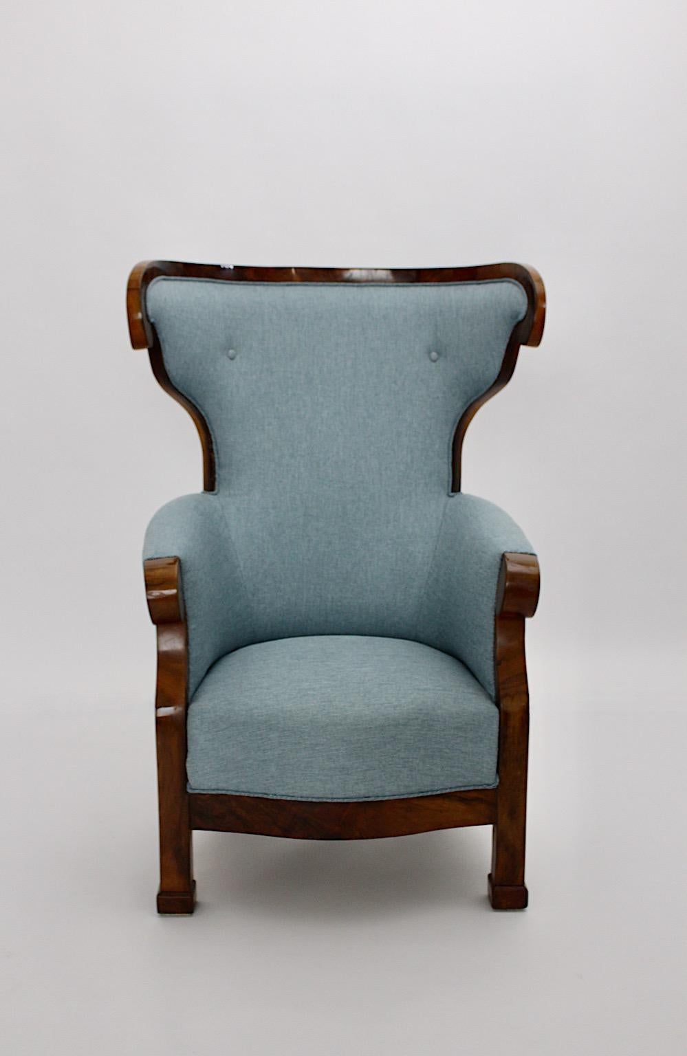 Biedermeier vintage wingback chair or armchair from walnut and sky blue upholstery designed and manufactured circa 1925 Vienna.
While the walnut frame in beautiful brown color tone is refinished some time ago and demonstrates stunning warmth and