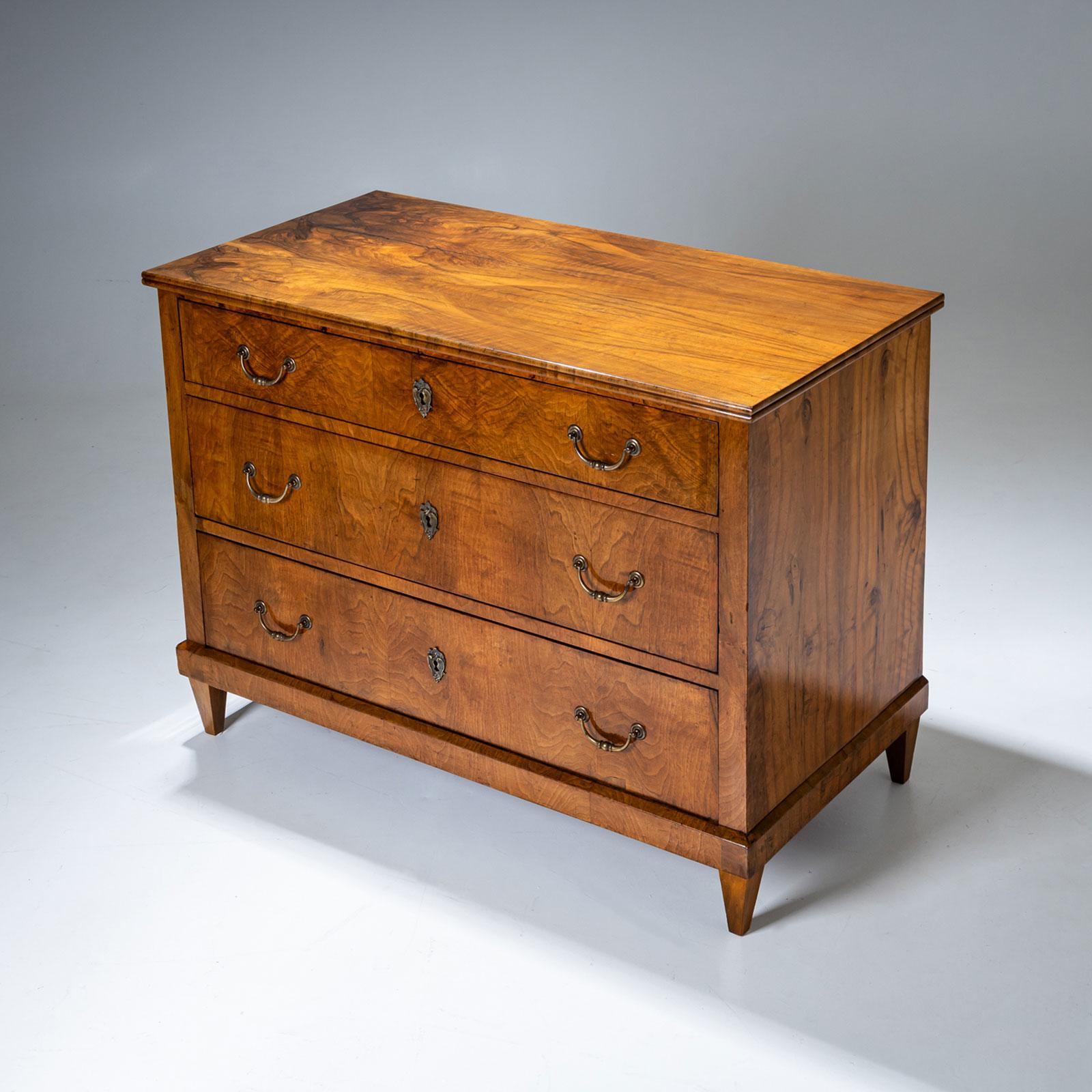 Una cassettiera Biedermeier a tre cassetti con maniglie in ottone, poggiata su basse gambe affusolate e impiallacciata in noce. È stato restaurato professionalmente e lucidato a mano.