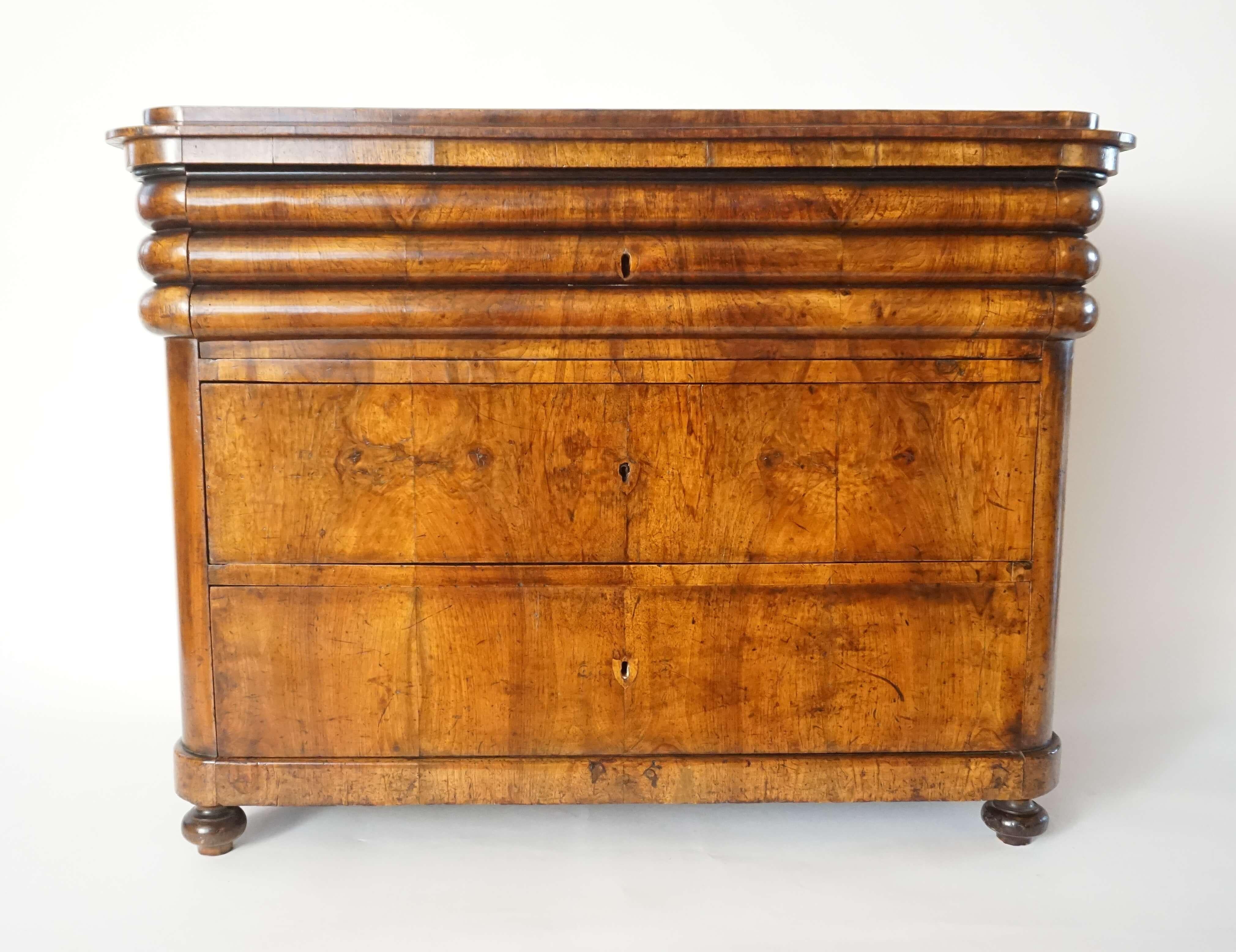 Highly unusual circa 1840 Austrian Biedermeier three-drawer commode or chest having walnut veneered D-form rectangular case; the stepped plinth-form top having rounded corners surmounting unique three-row 'tubular band' with concealed top drawer