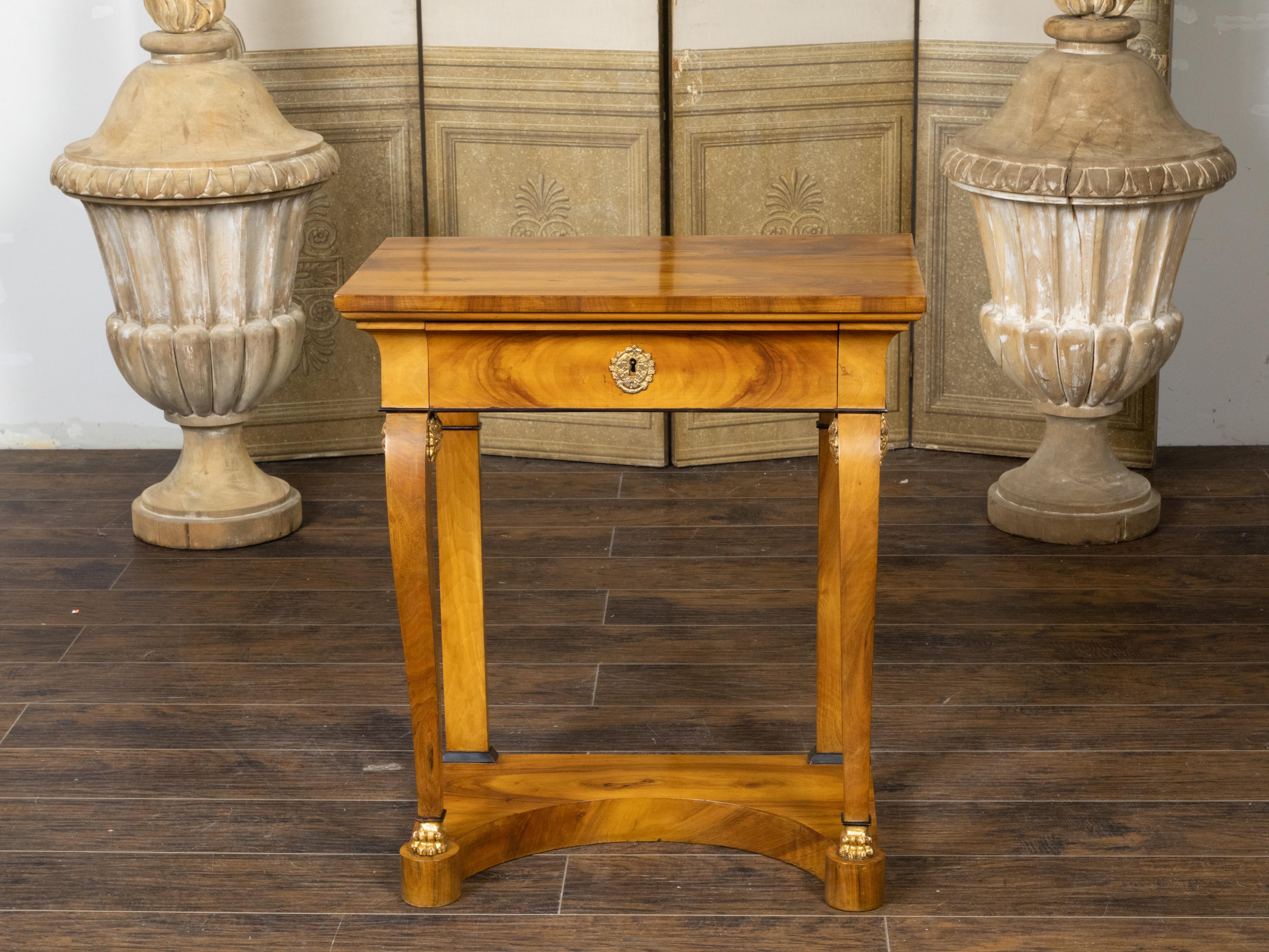 An Austrian Biedermeier period walnut console table from the 19th century, with single drawer, scrolling legs, lion paw feet, low shelf and carved rosettes. Created in Austria during the Biedermeier period, this walnut console table features a