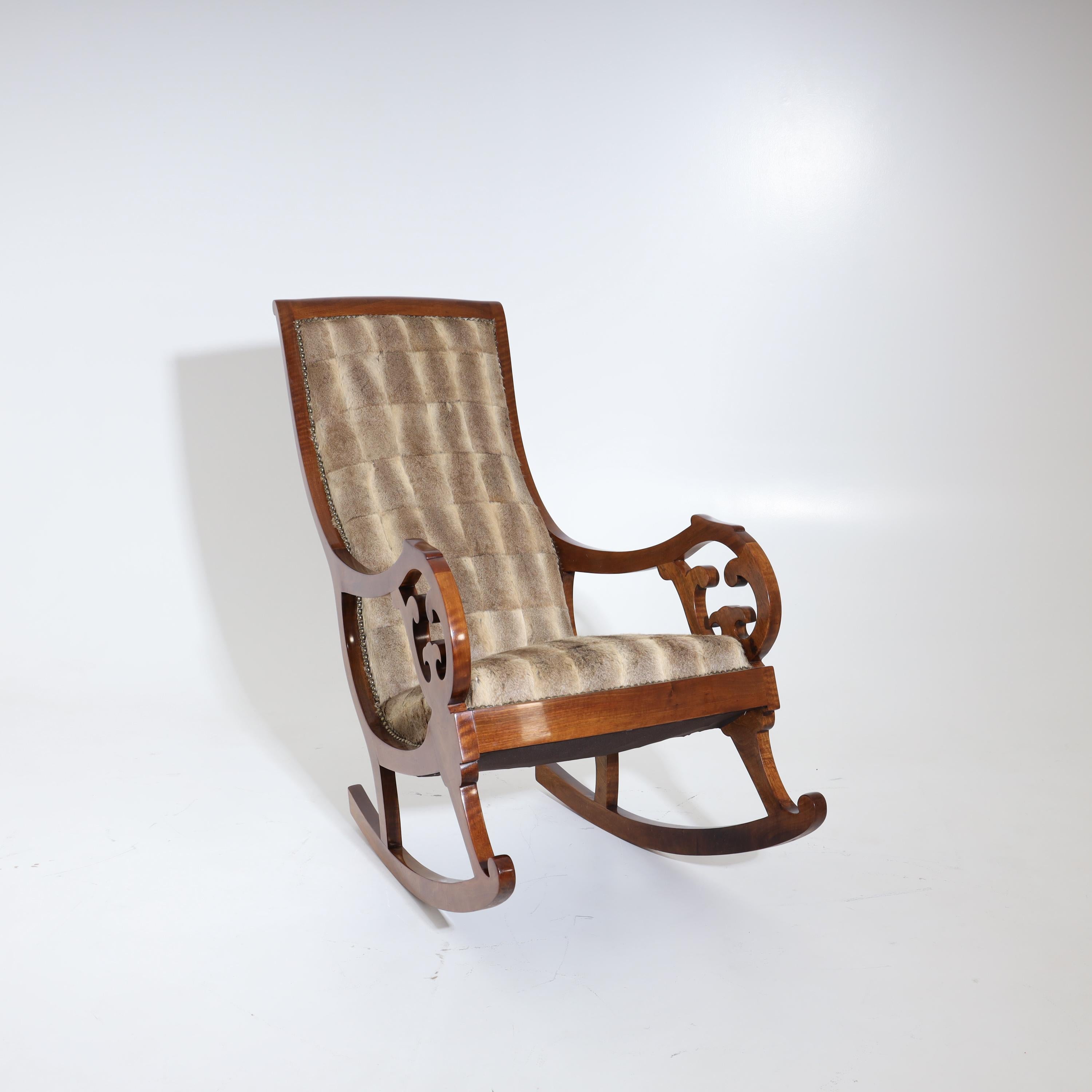 Walnut rocking chair with high backrest and armrests with stylized vine decoration. Seat and backrest were newly covered with fur and riveted.
  