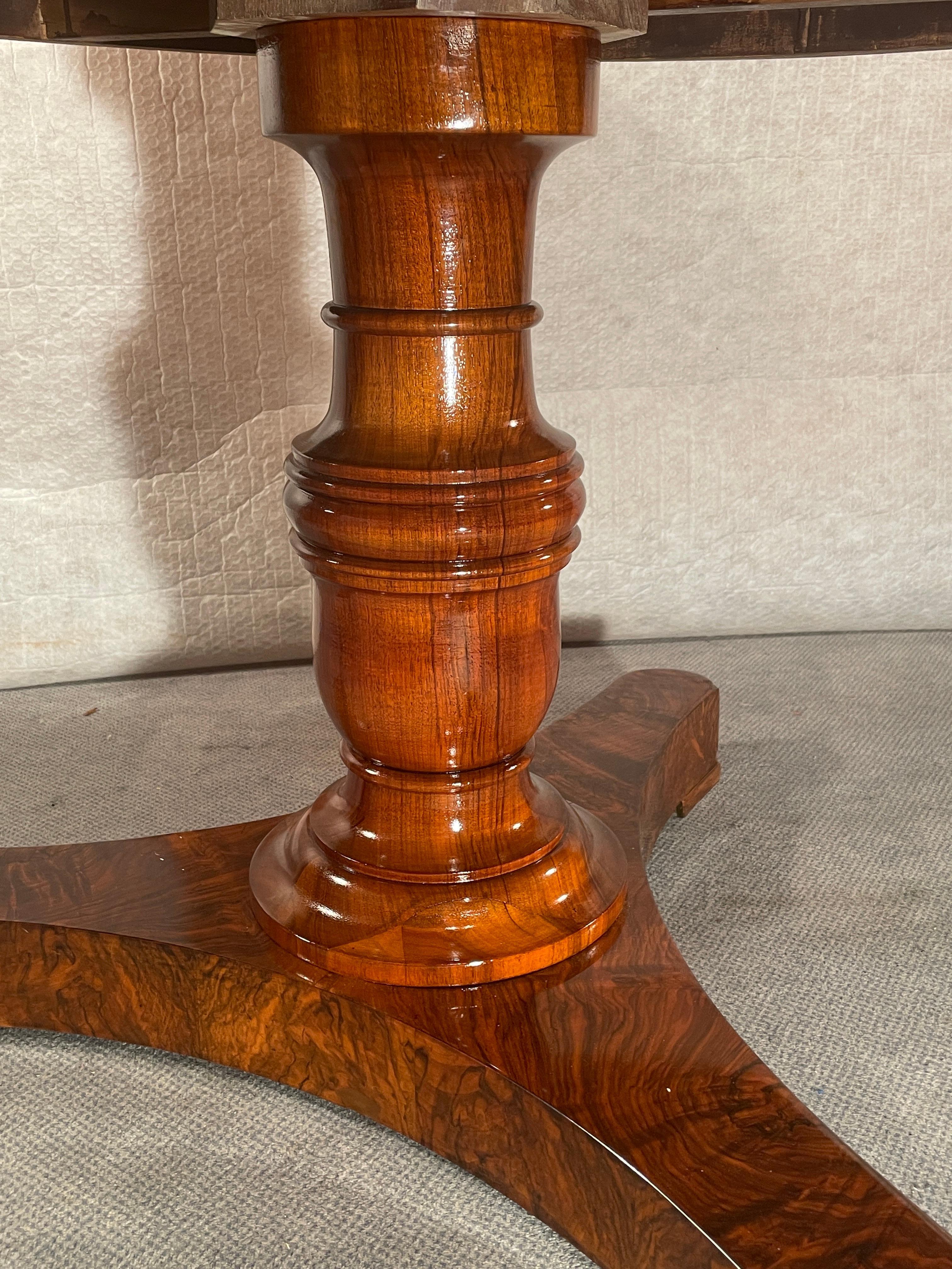 This gorgeous antique Biedermeier walnut table stands on a central baluster foot which rest on a trefoil base. The top has a very beautiful piecrust walnut root veneer. The trefoil base has a beautifully matching walnut veneer. The design of the