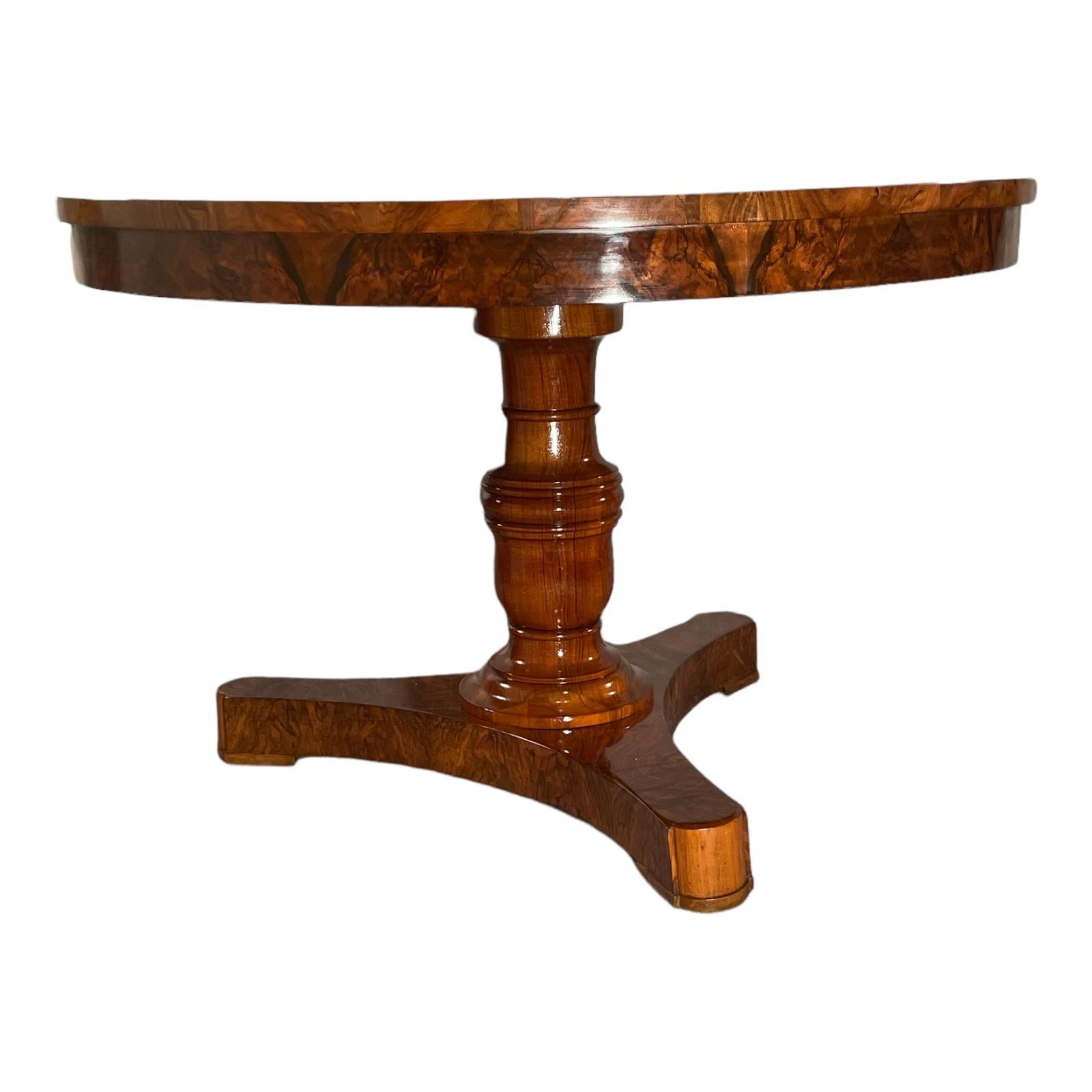 This gorgeous antique Biedermeier walnut table stands on a central baluster foot which rest on a trefoil base. The top has a very beautiful piecrust walnut root veneer. The trefoil base has a beautifully matching walnut veneer. The design of the