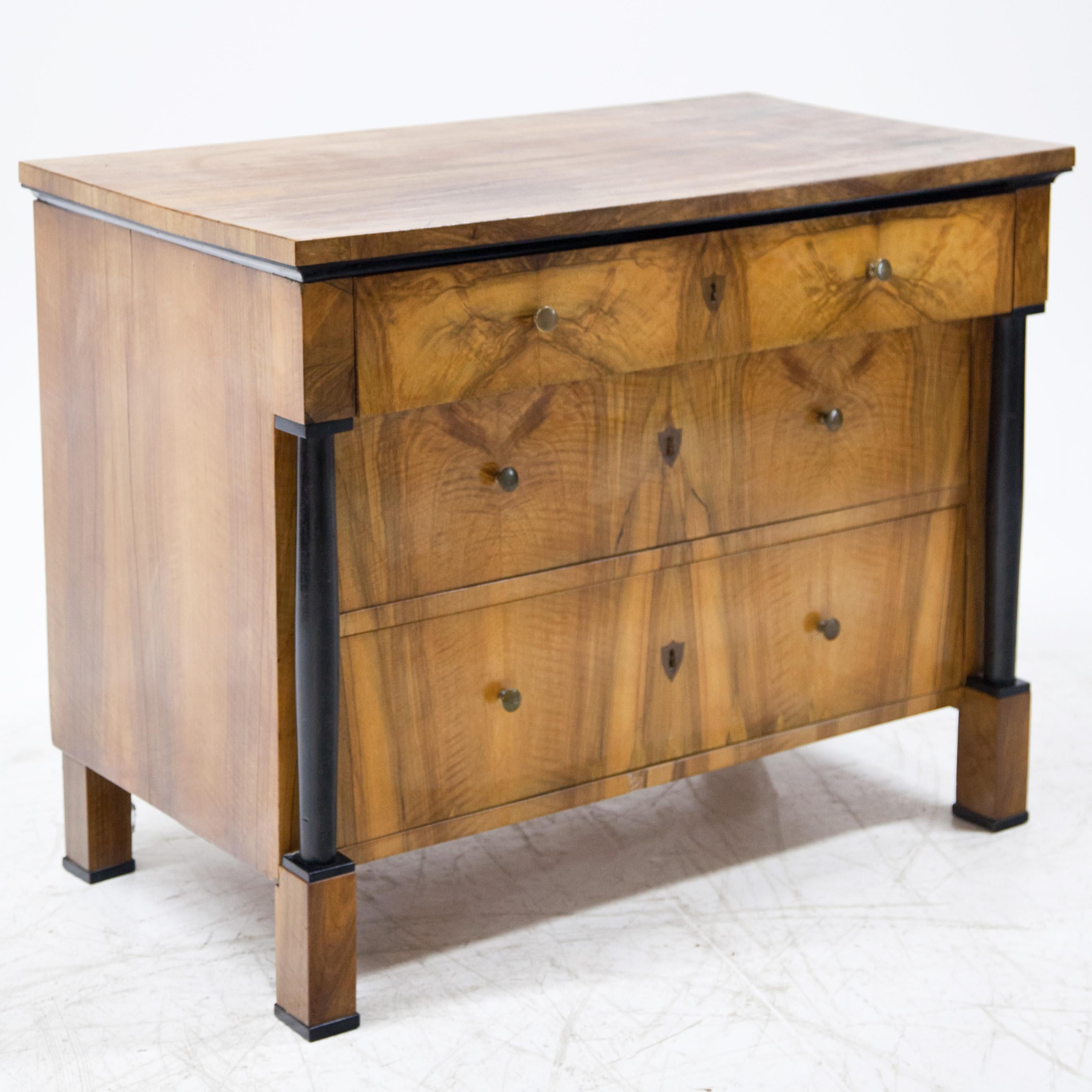Three-drawer Biedermeier chest of drawers on square feet veneered in walnut. The head drawer protrudes slightly and rests on ebonised full columns.