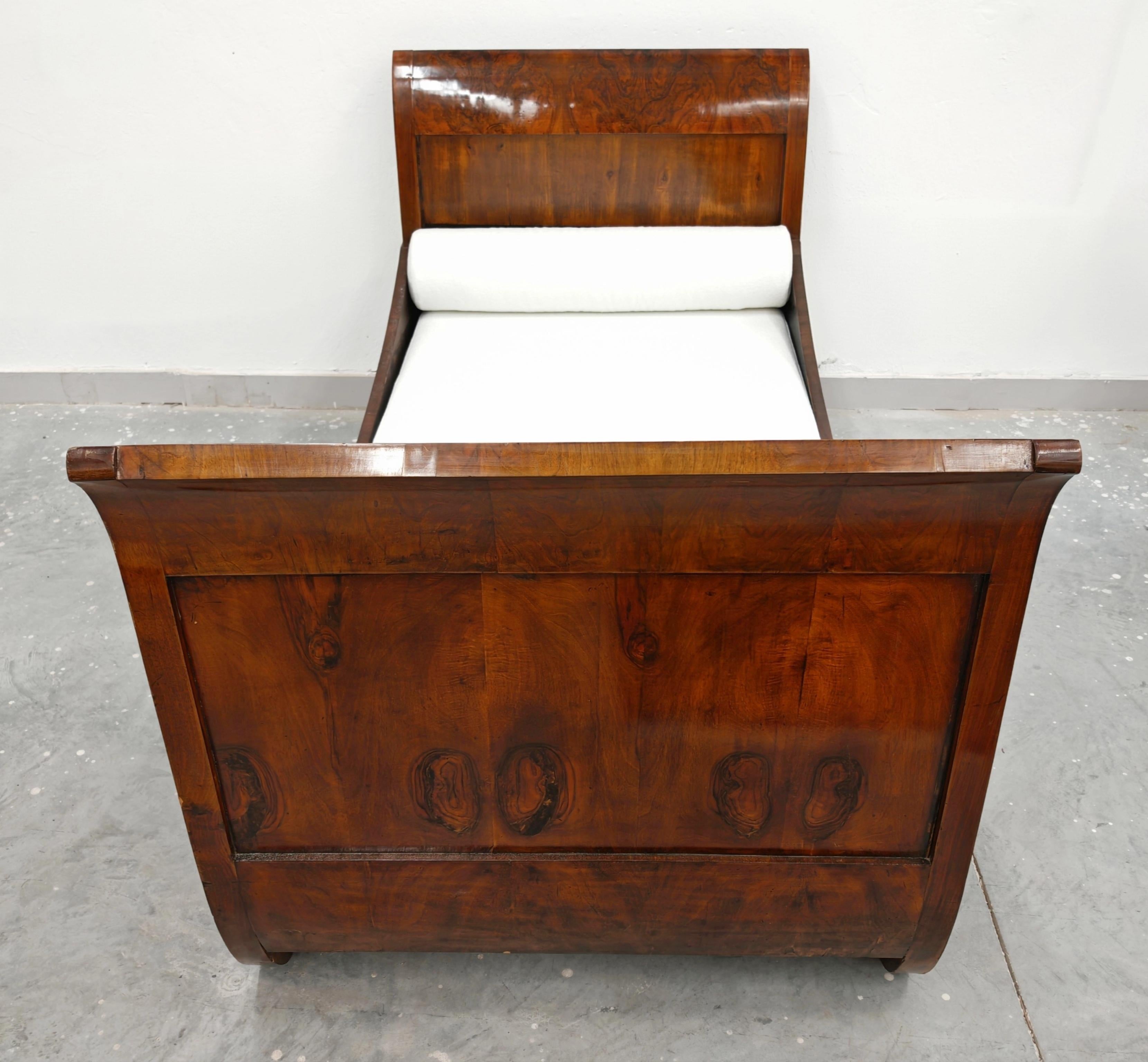 Dans cette annonce, vous trouverez un spectaculaire lit de jour Biedermeier ancien en placage de noyer. Le lit se caractérise par des têtes et des pieds de lit incurvés ou à volutes, ressemblant à un traîneau ou à une luge, d'où son nom commun. Le