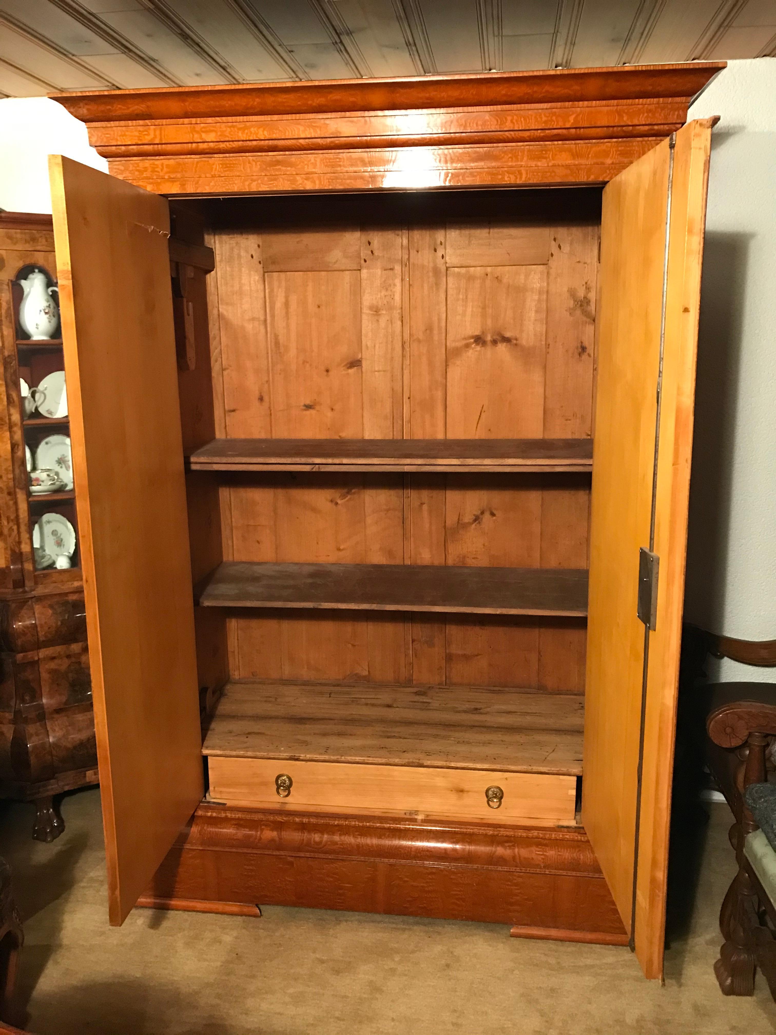 Biedermeier Wardrobe, Baltic States 1810-1820, Bird’s-eye maple veneer, filament inserts on the doors and the pilaster strips. Inside one drawer and a coat rack. Two shelves have been added later. The wardrobe is in very good condition. It will ship