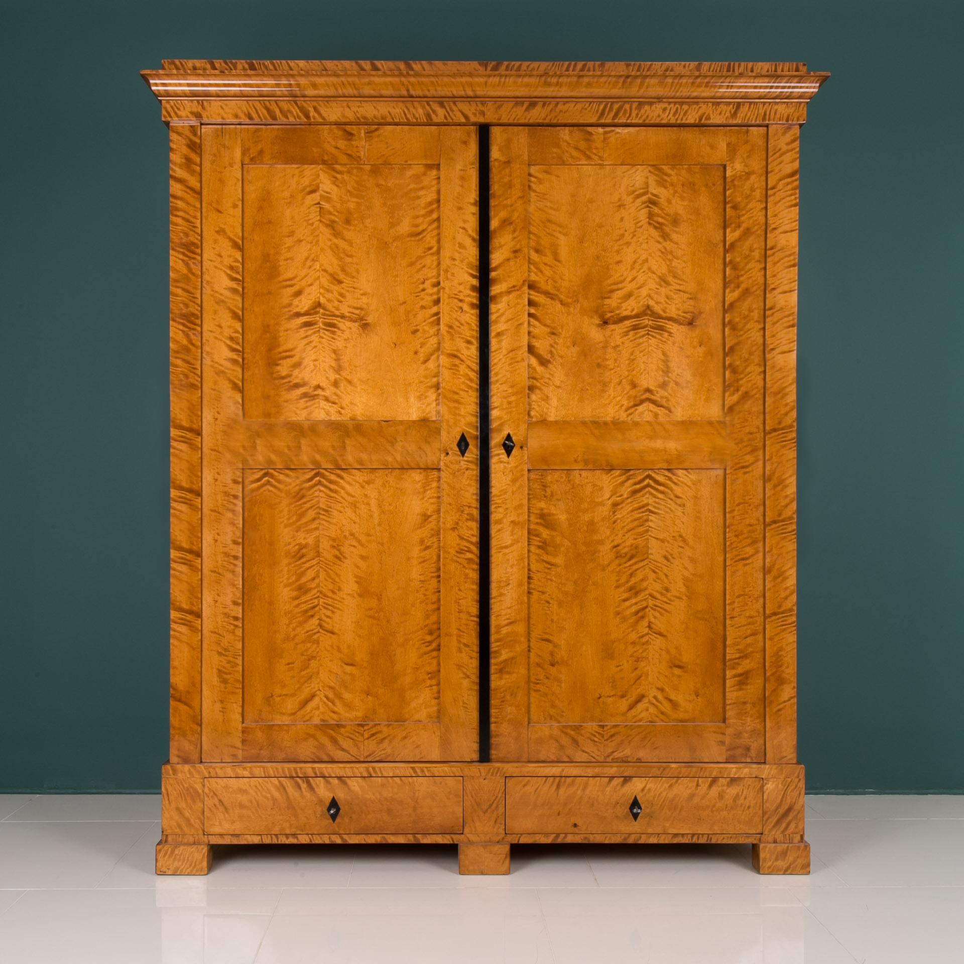 This Biedermeier wardrobe was made in Germany in first half of the 19th century. The piece is veneered with beautiful and rare flame birch veneer. Flame birch is known to show its beauty in various lighting that allows to show exquisite shades and