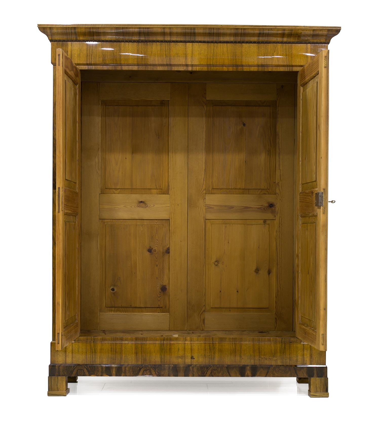 This Biedermeier wardrobe was made circa 1830 and is preserved in very good original condition. The piece was subjected to a very subtle, professional and careful renovation. The wardrobe is made of pine wood, veneered with walnut in a unique