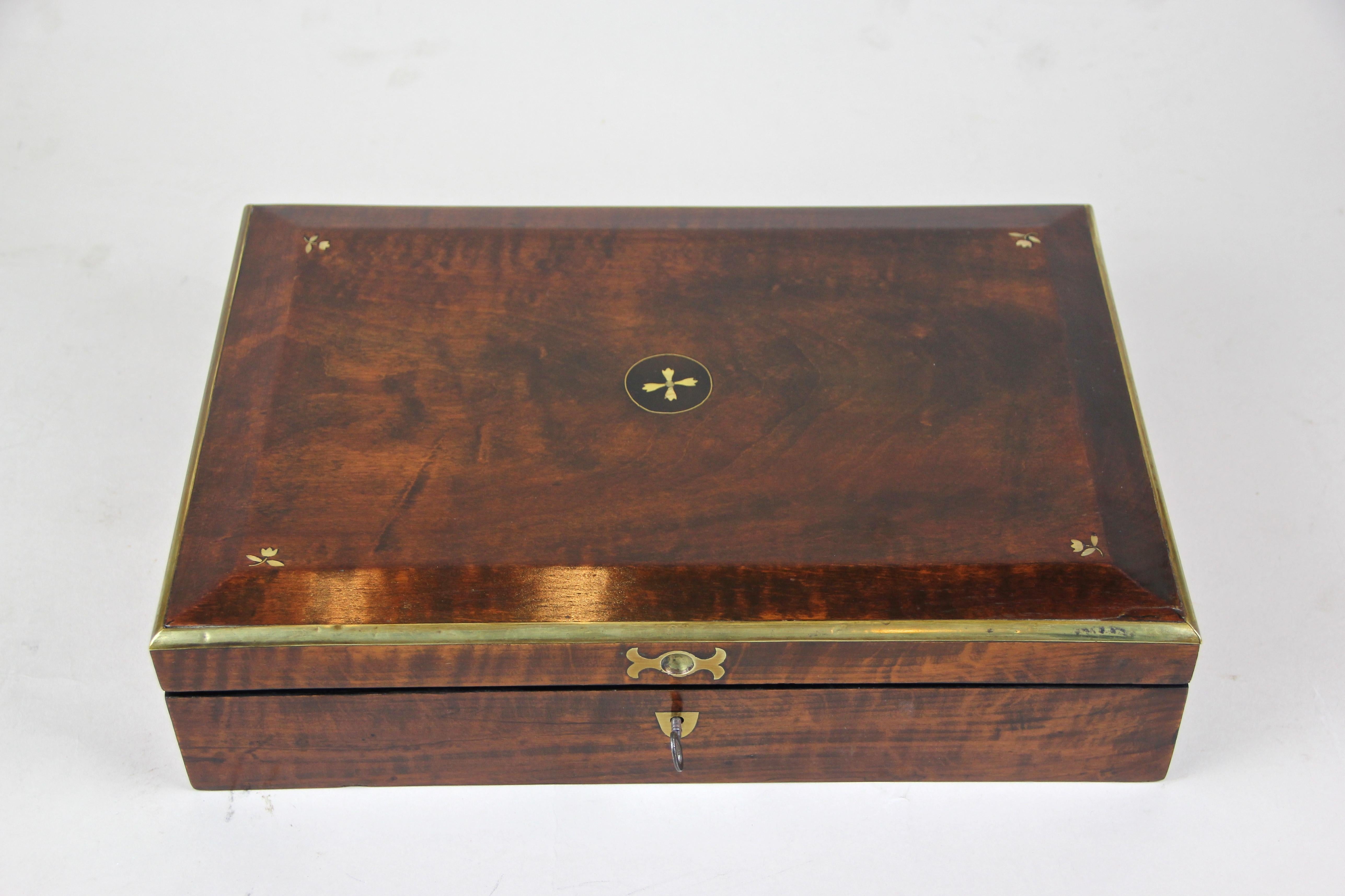 Precious Biedermeier wooden box out of Vienna/ Austria, circa 1830. This enchanting nut wood veneered box comes with wonderful brass framed edges on the lid, where you can also find beautiful small mother of pearl inlayed flowers. With an age over