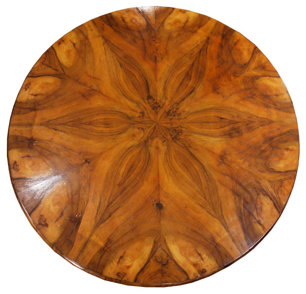 Round Biedermeier table in walnut and walnut root. The top is veneered in walnut, divided into twelve segments to create suggestive veining games. The central ball-shaped stem is flanked by three shaped and carved uprights. Small triangular base.