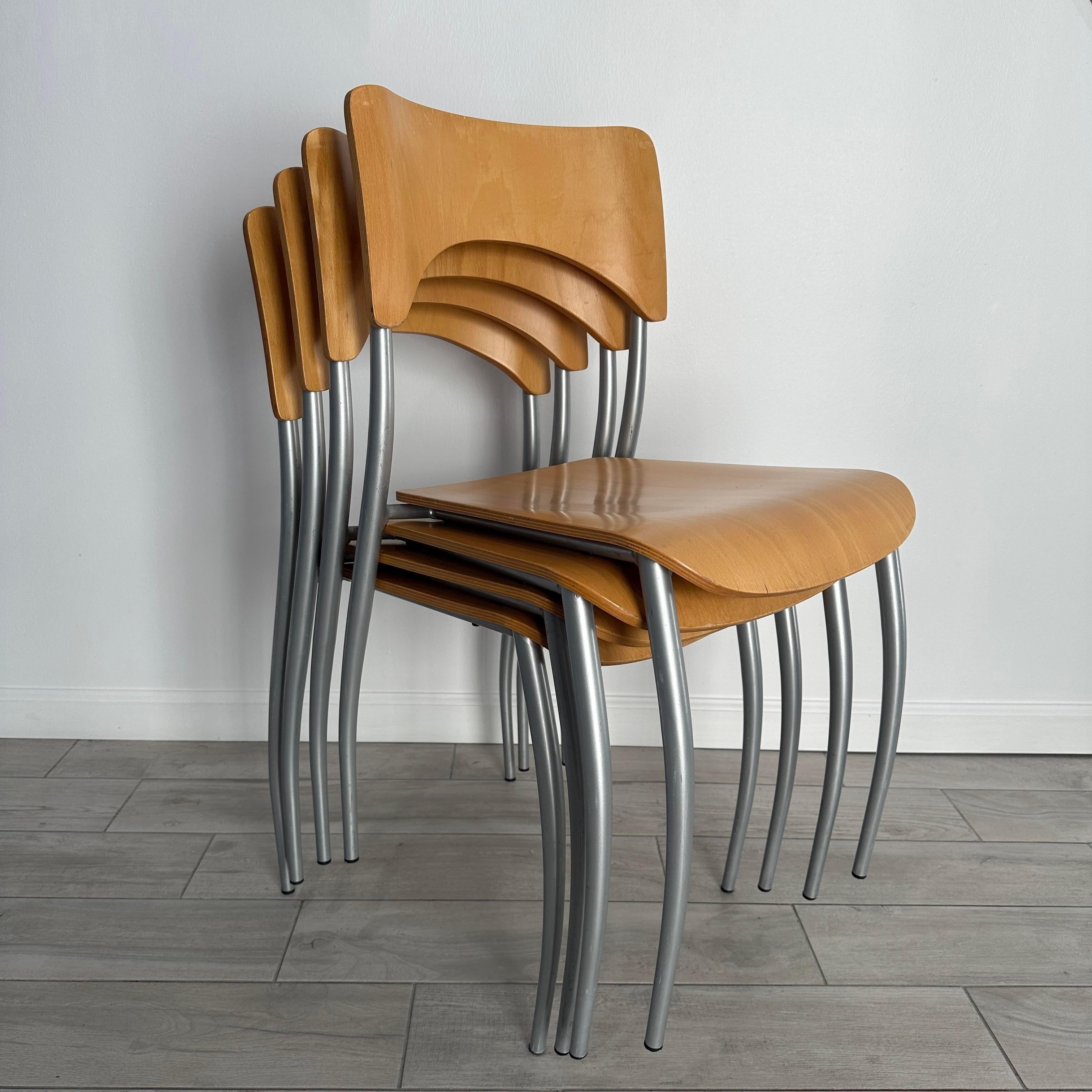 Raro juego de 4 sillas vintage Bieffeplast Italia con asientos de madera curvada y patas de metal plateado. Los asientos están curvados para tener una estética escultural que continúa con la forma de las patas. Las sillas son apilables para ahorrar