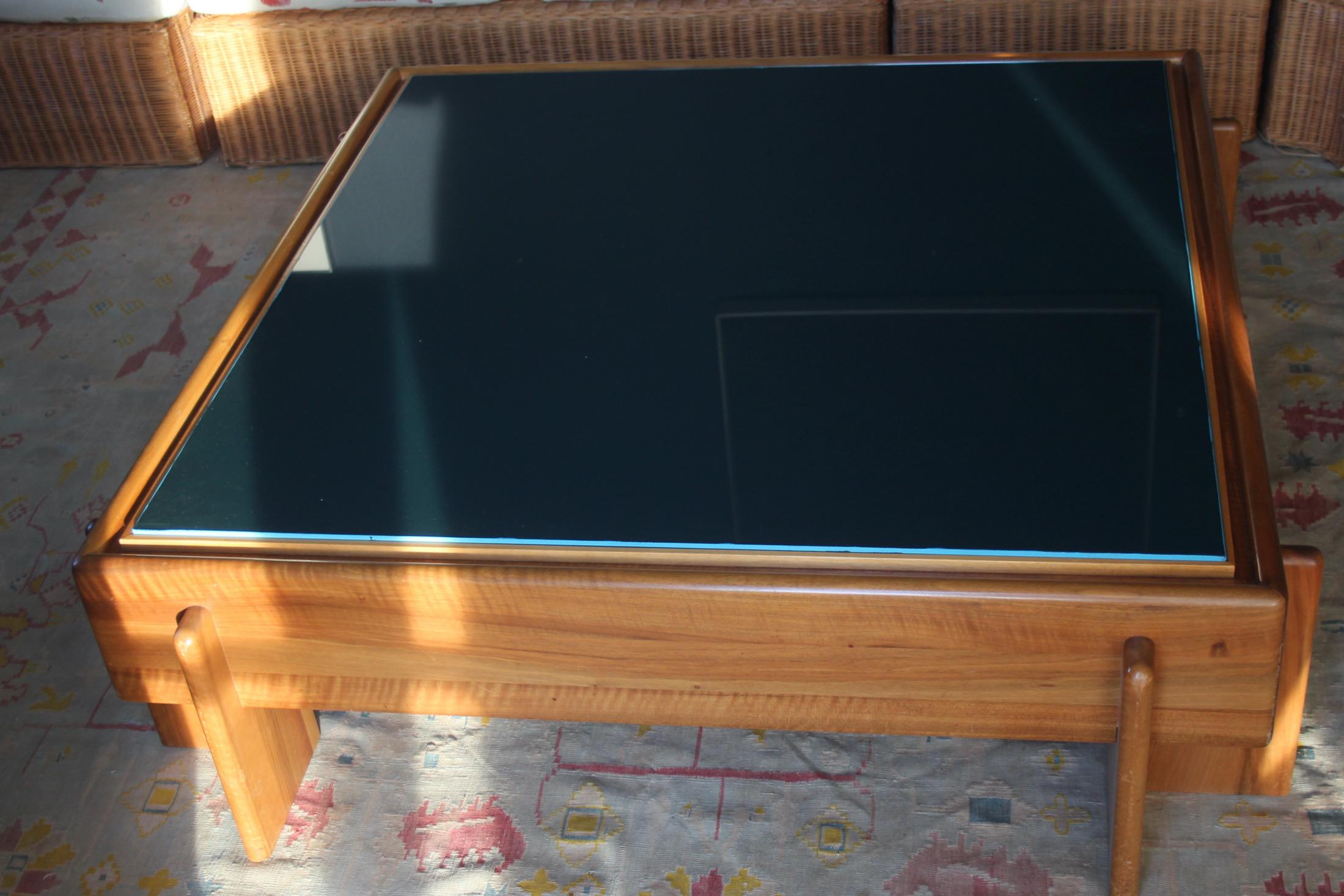 large coffee table in the style of Afra and Tobia Scarpa, in honey-colored wood and blue-painted glass, there is a central board under the glass on which there is a glued carpet and the glass is placed on top