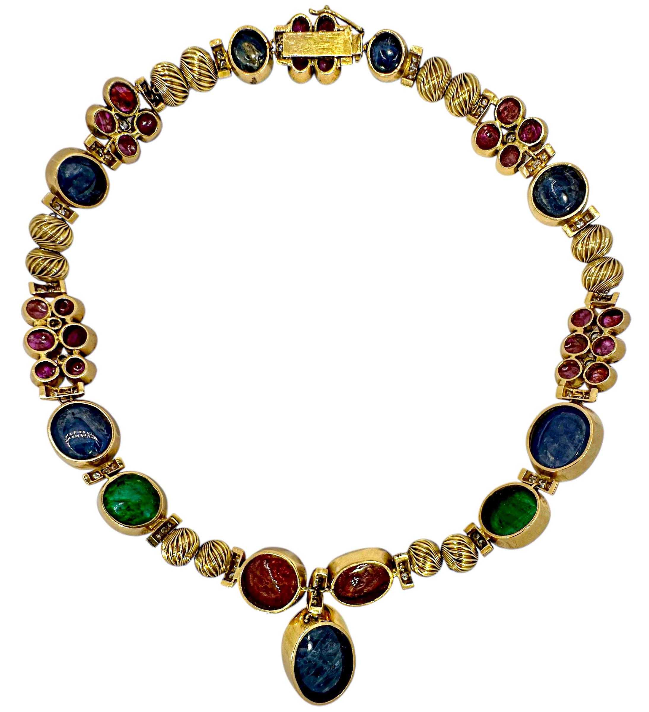 Questa esclusiva collana in oro giallo a girocollo della metà del XX secolo evoca puro stile e drammaticità. Un totale di undici grandi rubini, smeraldi e zaffiri cabochon, incastonati in oro 18 carati, sono punti focali del design. Sono accentuati
