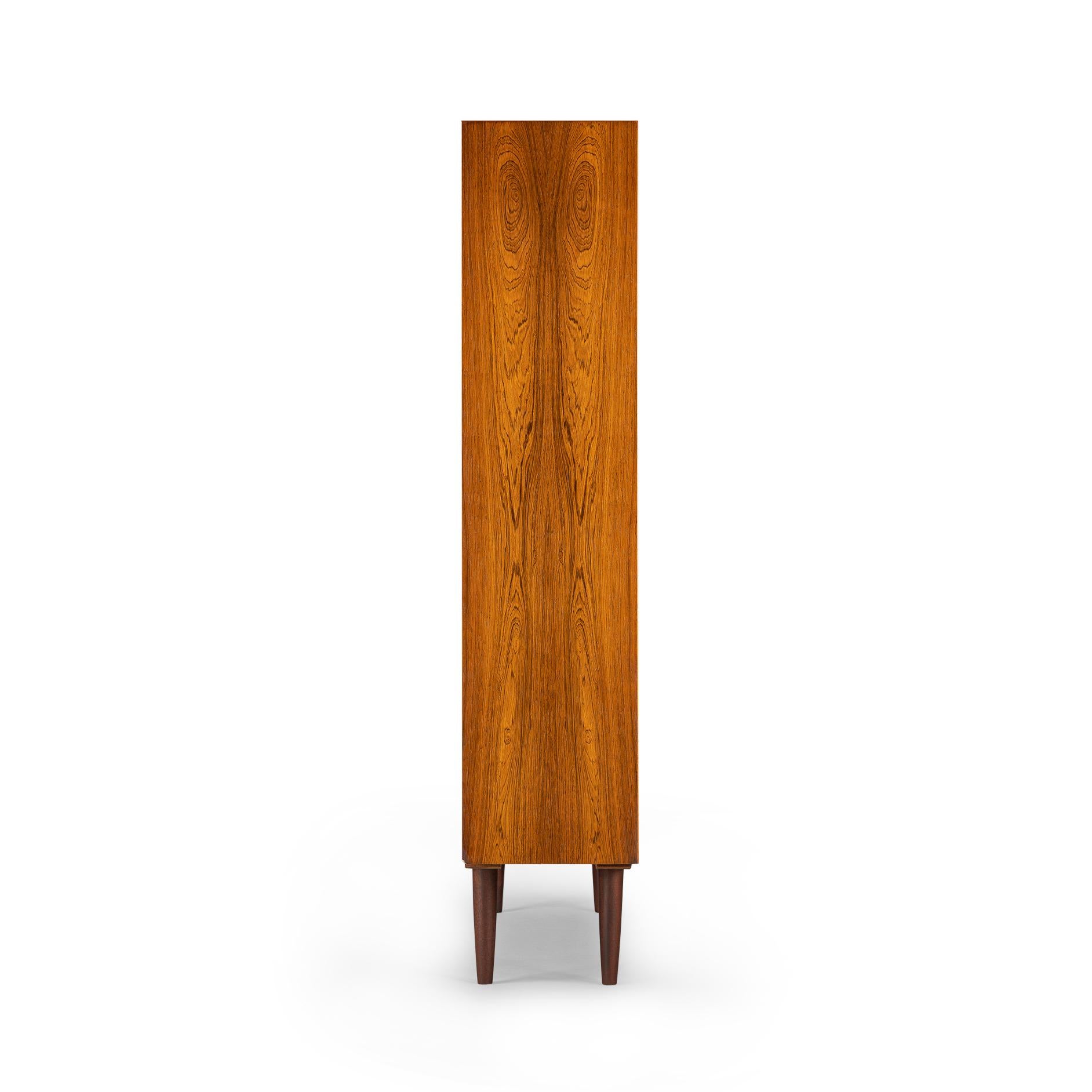 Danish tall bookcase in beautiful hardwood veneer. Designed by Carlo Jensen and made by Hundevad & Co. This bookcase is in very good vintage condition and has a total of 8 height-adjustable shelves.