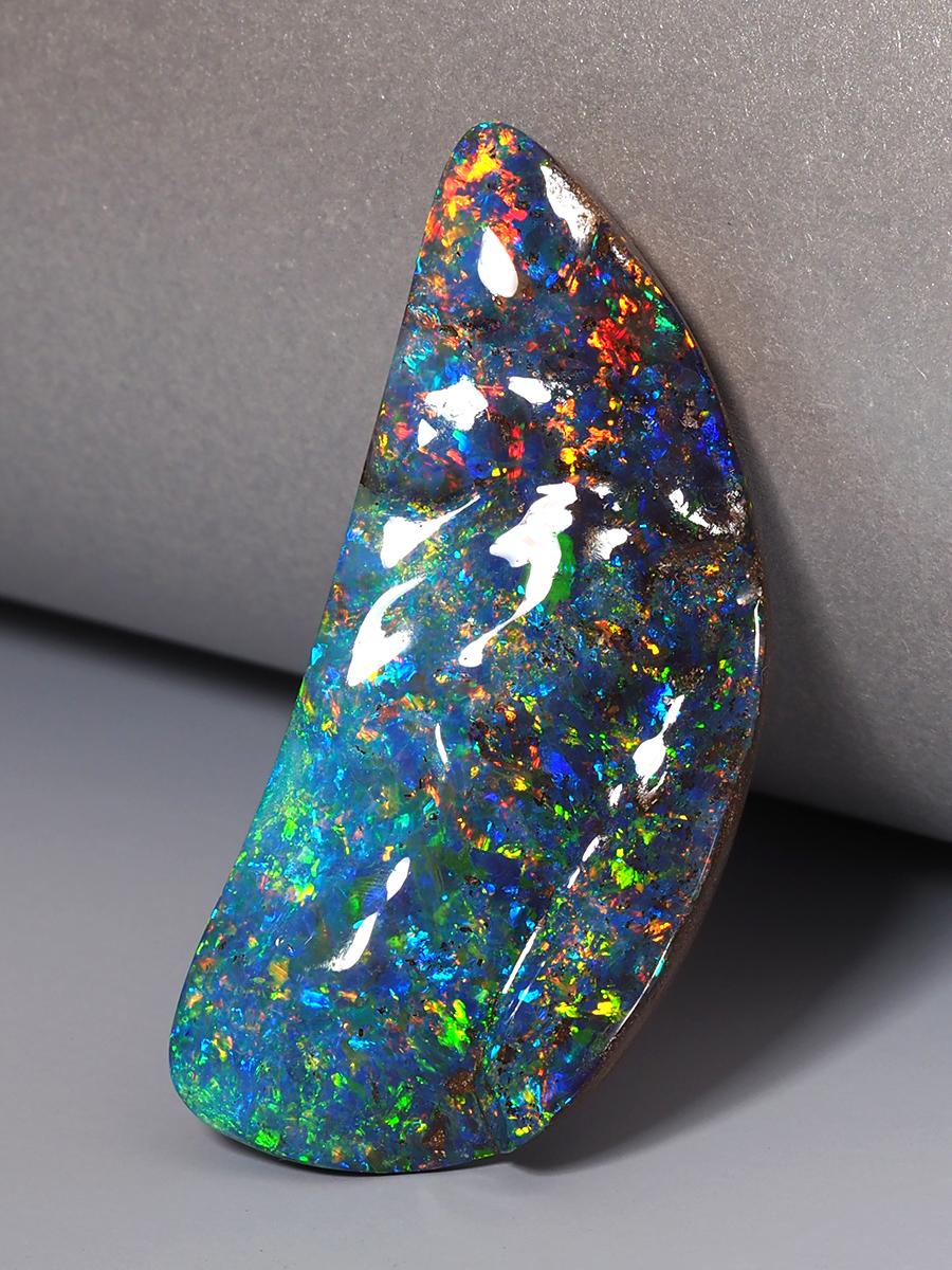 Boulder Opal aus Queensland, Australien, ist einer der seltensten Edelsteine der Welt.
Dieser Opal von 47,50 Karat in freier Form ist spektakulär in Größe, Farbe und Form und zeigt einen vollen Regenbogen von Farben. Er ist ein Stein in