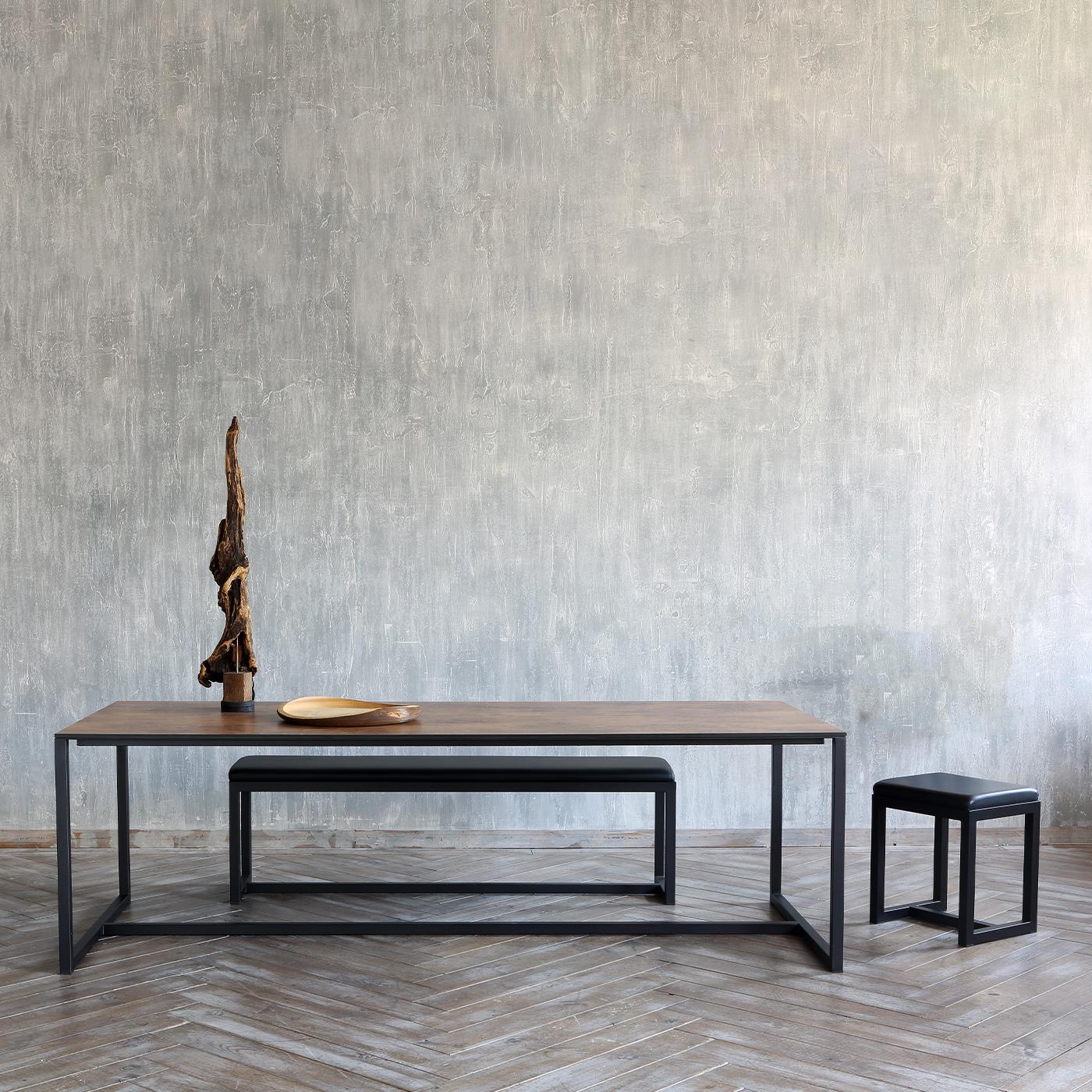 Cette banquette linéaire de Maurizio Peregalli allie une simplicité élégante à un confort absolu. La structure en cuivre du fauteuil, reliée par une ligne structurelle à la base, présente une finition raffinée en noir sablé - également disponible