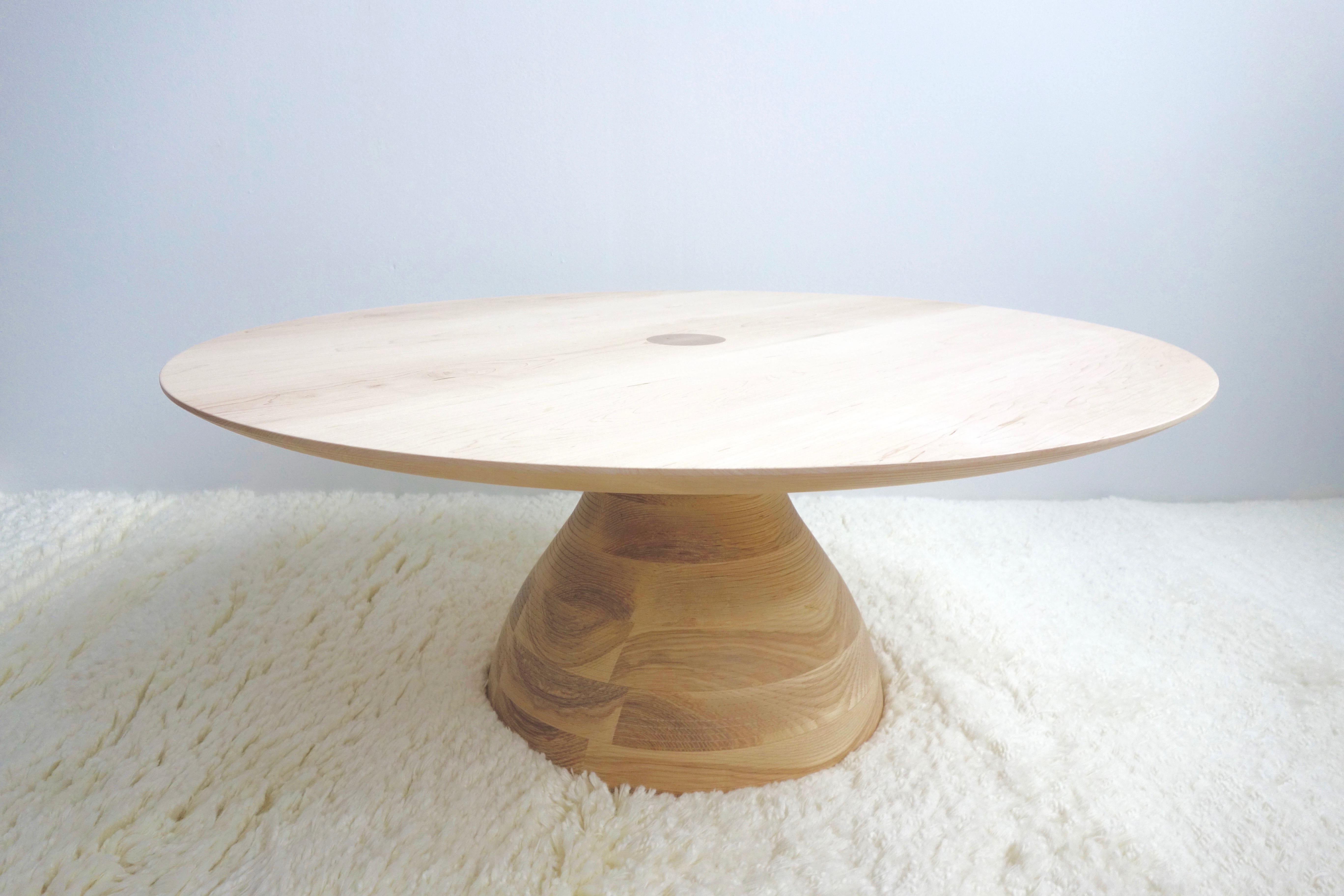 The ash base is stack-laminated and then turned on a large lathe. The tabletop of selected hardwoods is also mounted and turned to achieve its tapered and grooved edge detail. Voluminous yet elegant, sculptural, and simple. The table comes in