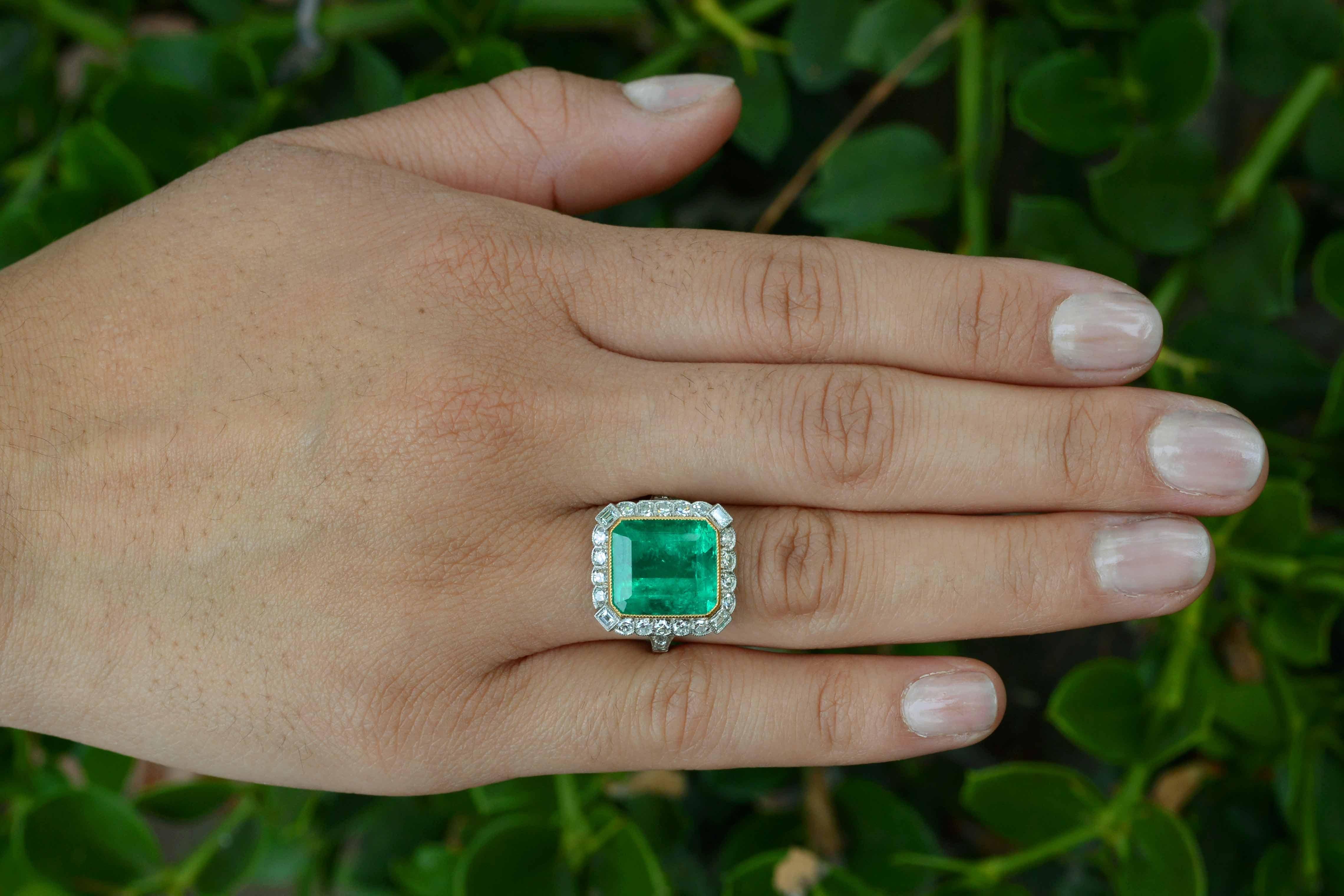 You will be instantly captivated by the lush, verdant green Emerald, weighing a substantial 6.70 carat with a richly saturated, vivid, medium-dark tone. Fabricated in an Art Deco revival platinum setting with a fascinating pierced, openwork under