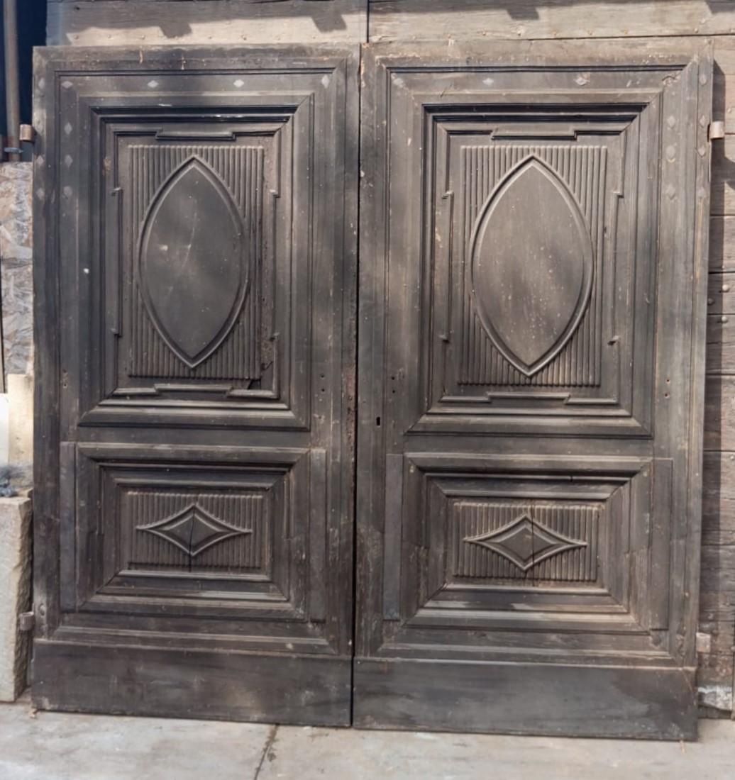 Antique Grande porte d'entrée, porte principale en noyer massif, sculptée à la main avec des panneaux et un double battant, deux portes avec des panneaux sculptés dans des formes géométriques. Le dos est laqué. Origine : Piémont (Italie), original