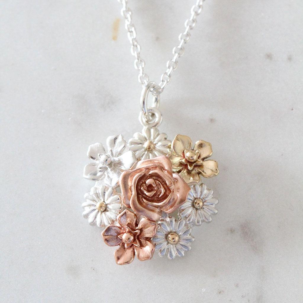 The big flower bouquet necklace features forget-me-not flowers, daisies, and a rose. The meaning of each flower is remembrance and good memories; innocence and new beginning; red rose, 