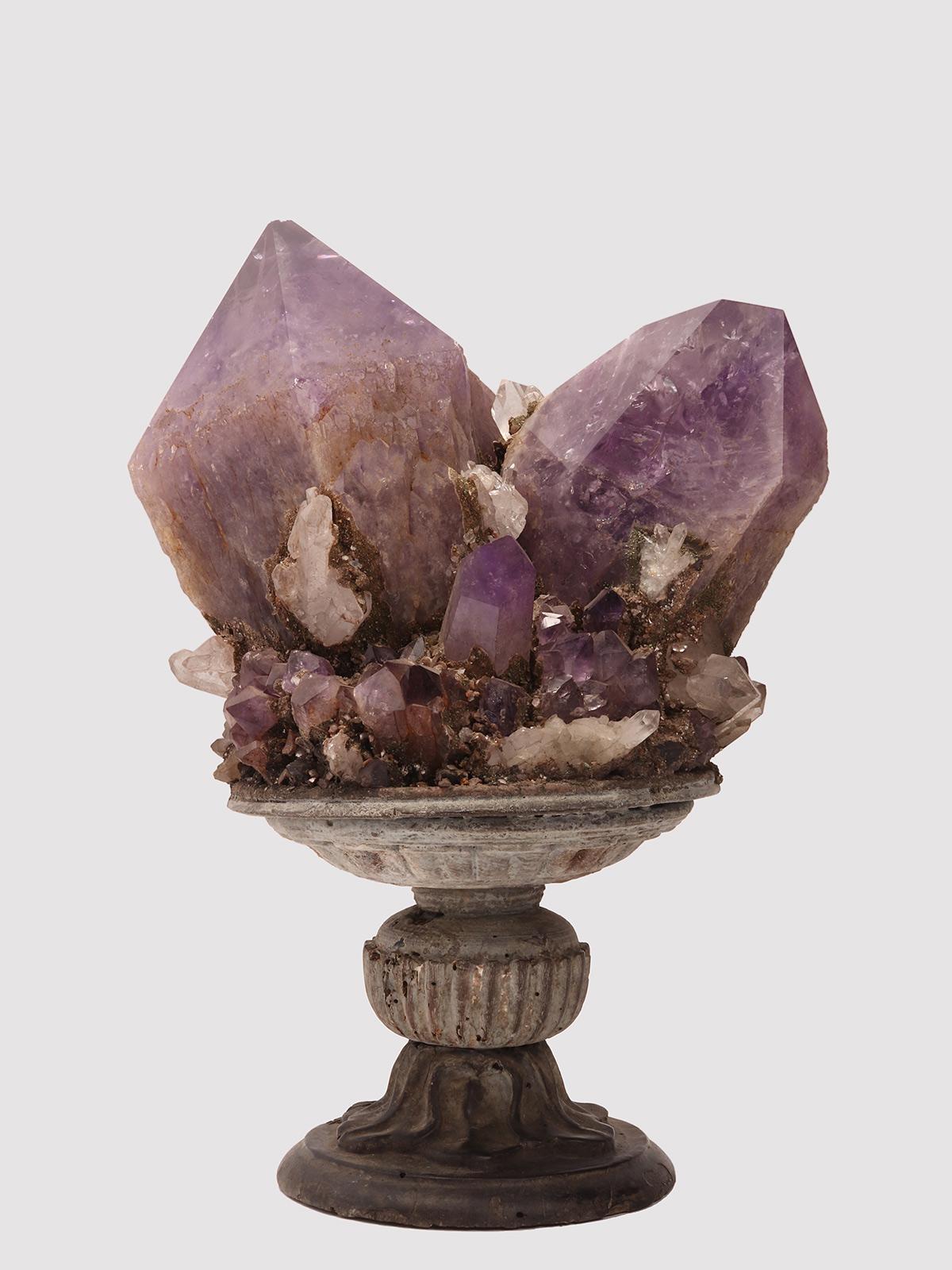 Un ejemplar de mineral de Naturalia. Gran drusa con cristales de amatista y cuarzo, montada sobre una base de madera lacada gris en forma de jarrón. Italia, hacia 1870.